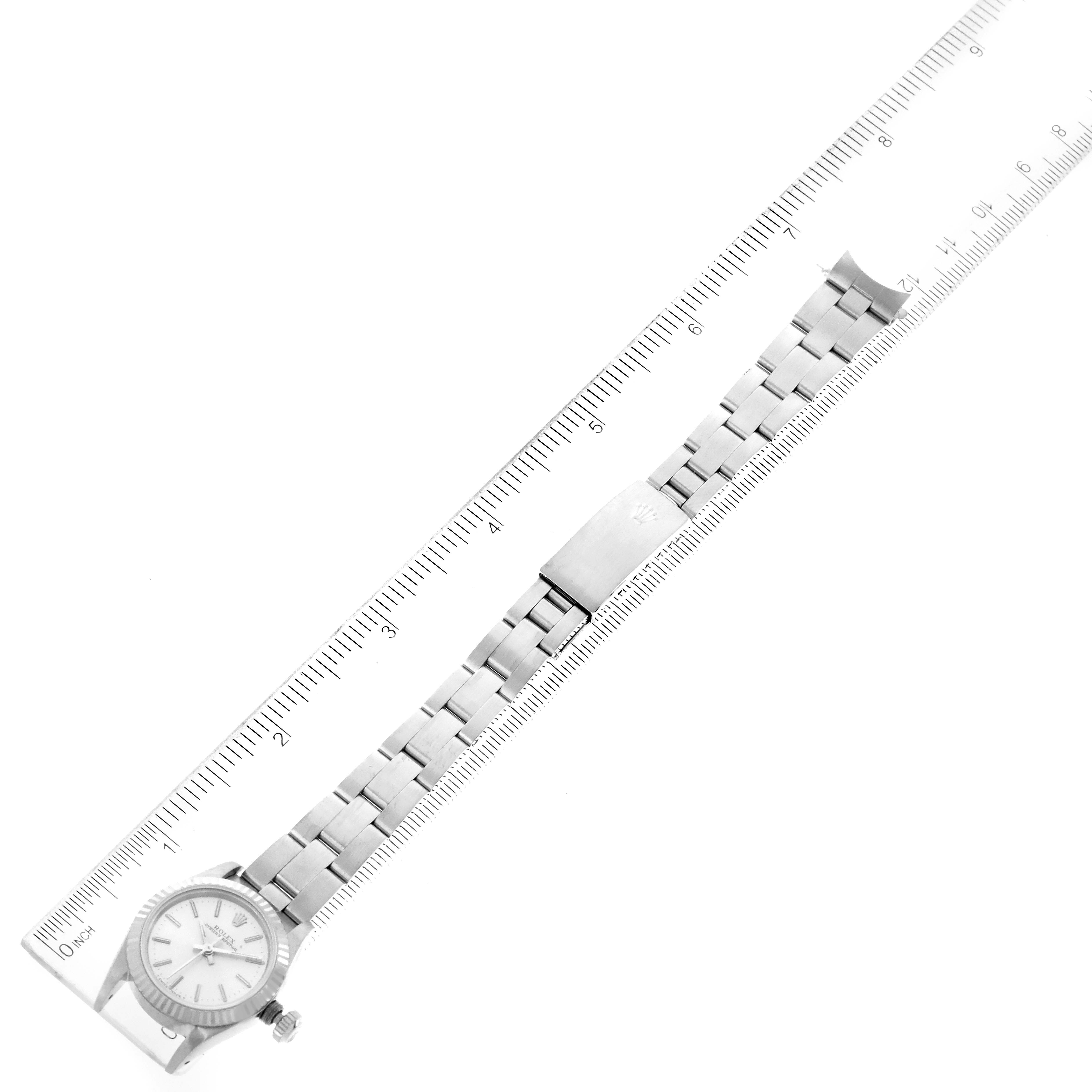 This image shows a top view of a Rolex Oyster Perpetual 67194 Women's Stainless Steel Silver Dial 67194 Women's Stainless Steel Silver Dial watch and its metal bracelet, placed alongside a ruler for measurement.
