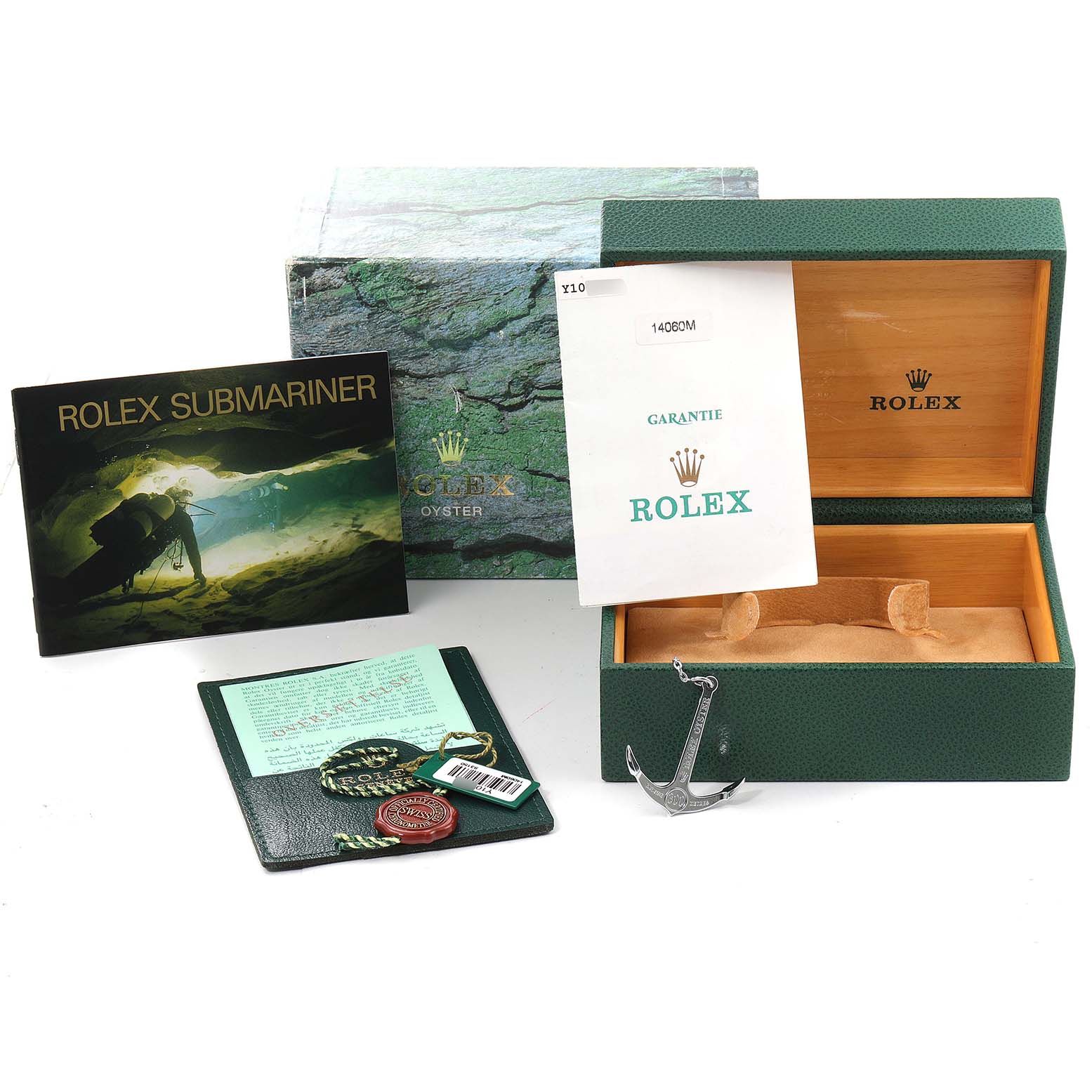 The image shows the packaging, warranty booklet, instruction manual, tag, and an anchor accessory for the Rolex Submariner 14060 Men
s Stainless Steel Black Dial 14060 Men
s Stainless Steel Black Dial watch.