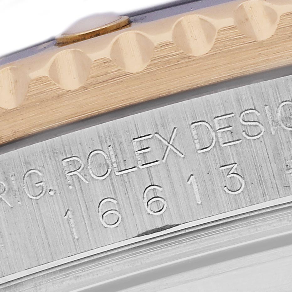 The image shows a close-up of the Rolex Submariner 16613 Men's Steel and Gold (two tone) Blue Dial 16613 Men's Steel and Gold (two tone) Blue Dial's bezel edge and engraved case detail.