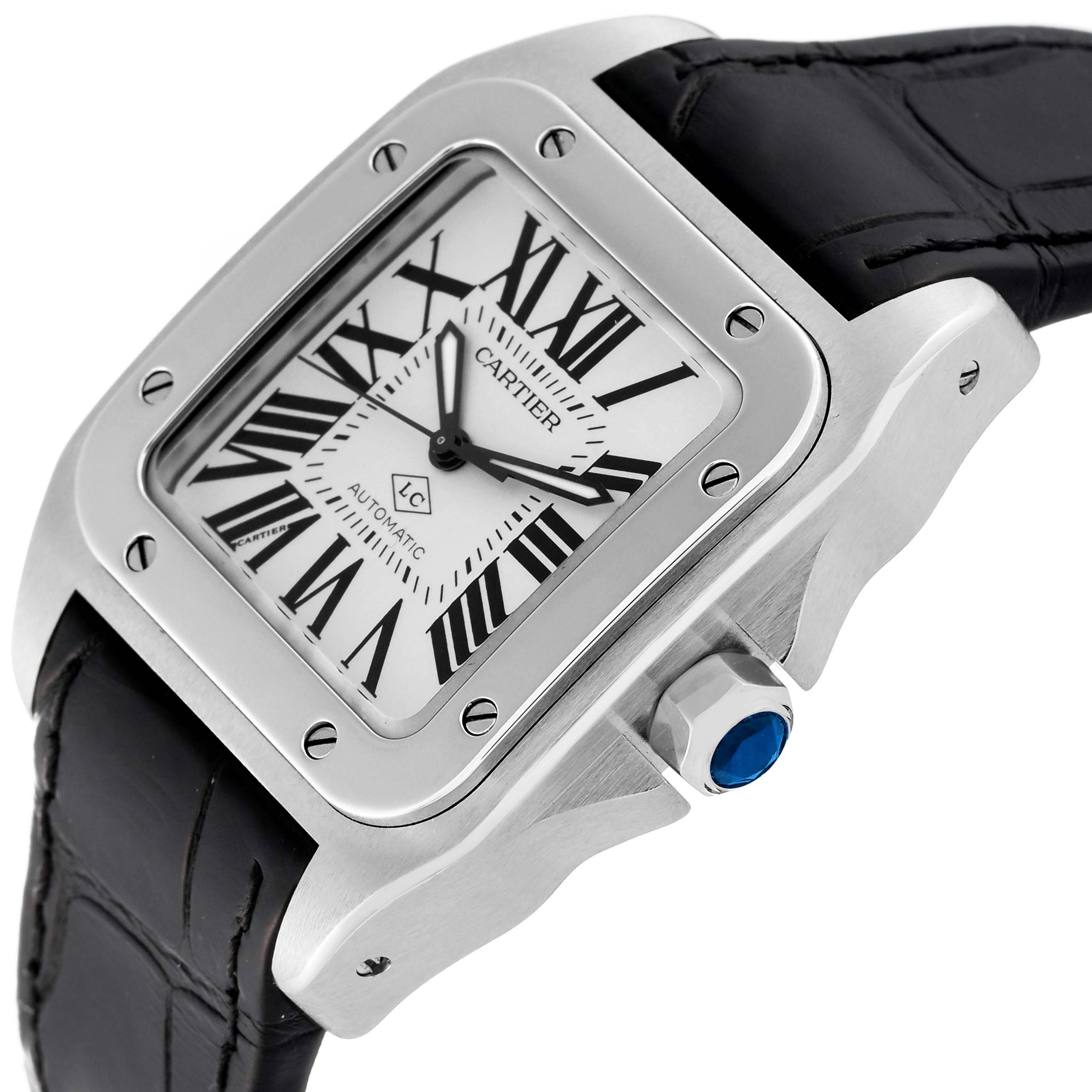 The image shows a close-up of the Cartier Santos WSSA0008 Men
s Stainless Steel Silver Dial WSSA0008 Men
s Stainless Steel Silver Dial watch, highlighting the dial, bezel, crown with a blue gem, and part of the strap.