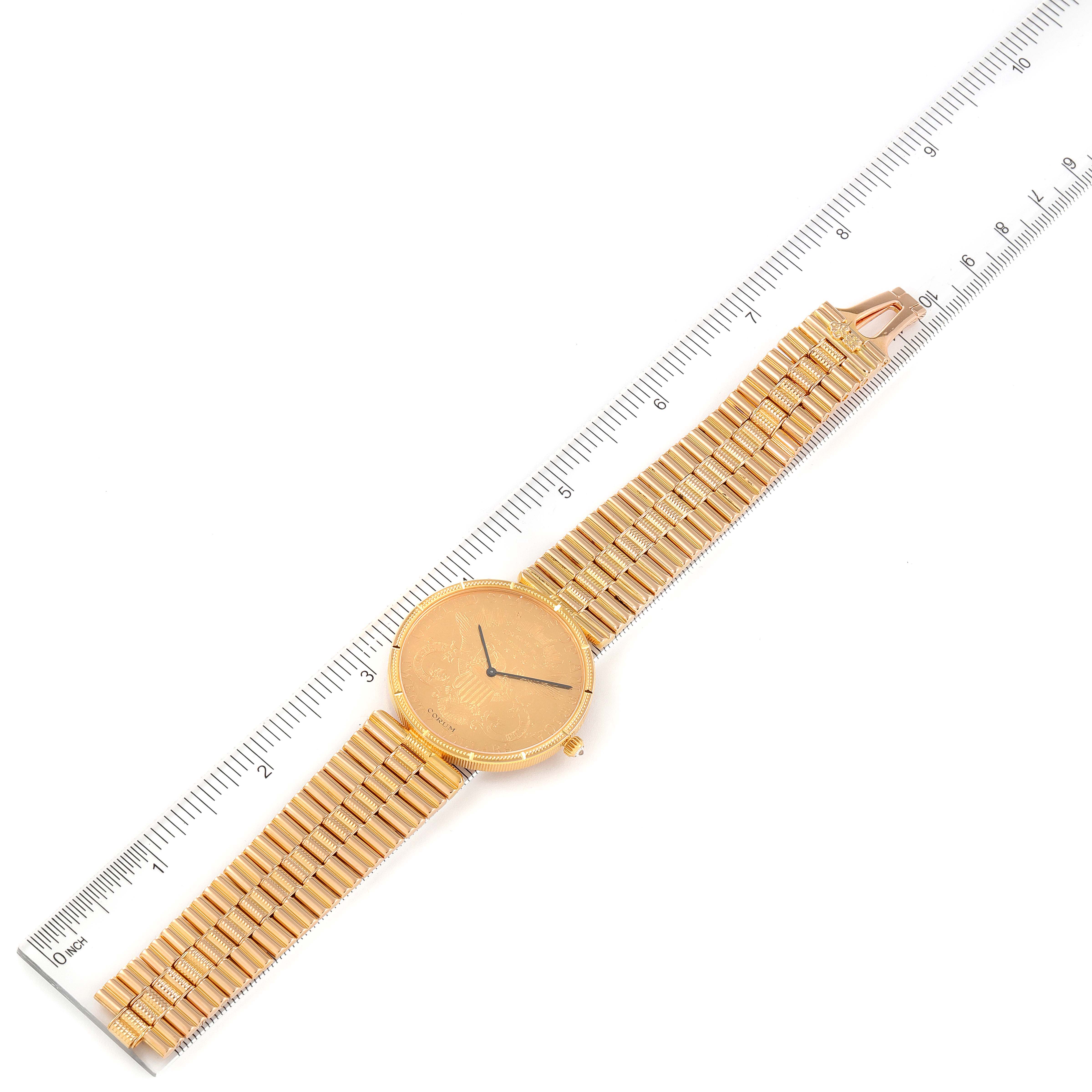 The image shows a Corum Coin Watch Men's Yellow Gold Black Dial Men's Yellow Gold Black Dial model placed at a slight angle, with a ruler for scale, displaying the face, bezel, and bracelet.