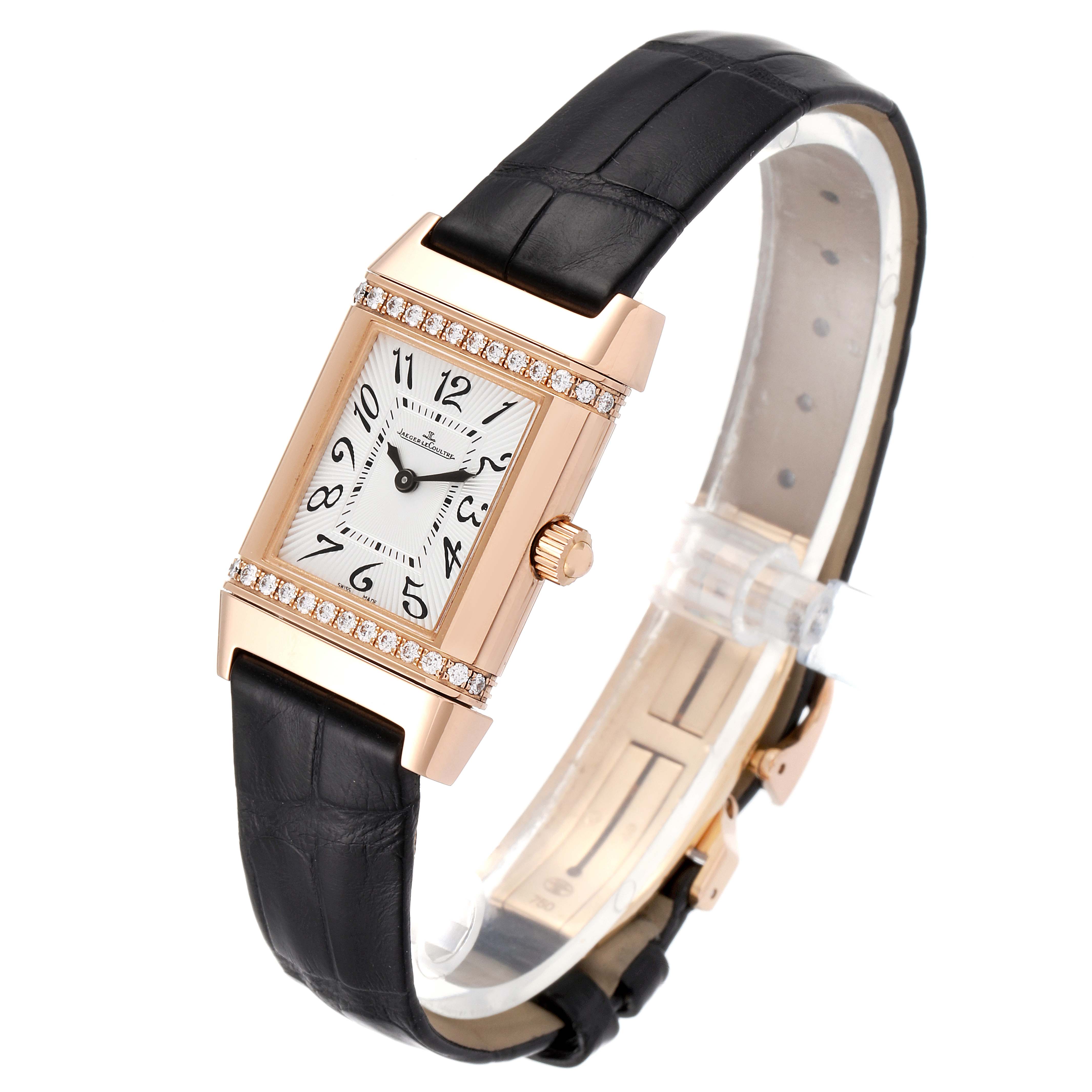 This image shows a Jaeger LeCoultre Reverso Q2651430 Women's Rose Gold Silver Dial Q2651430 Women's Rose Gold Silver Dial watch with a rectangular dial, gold case, black leather strap, and diamond accents.