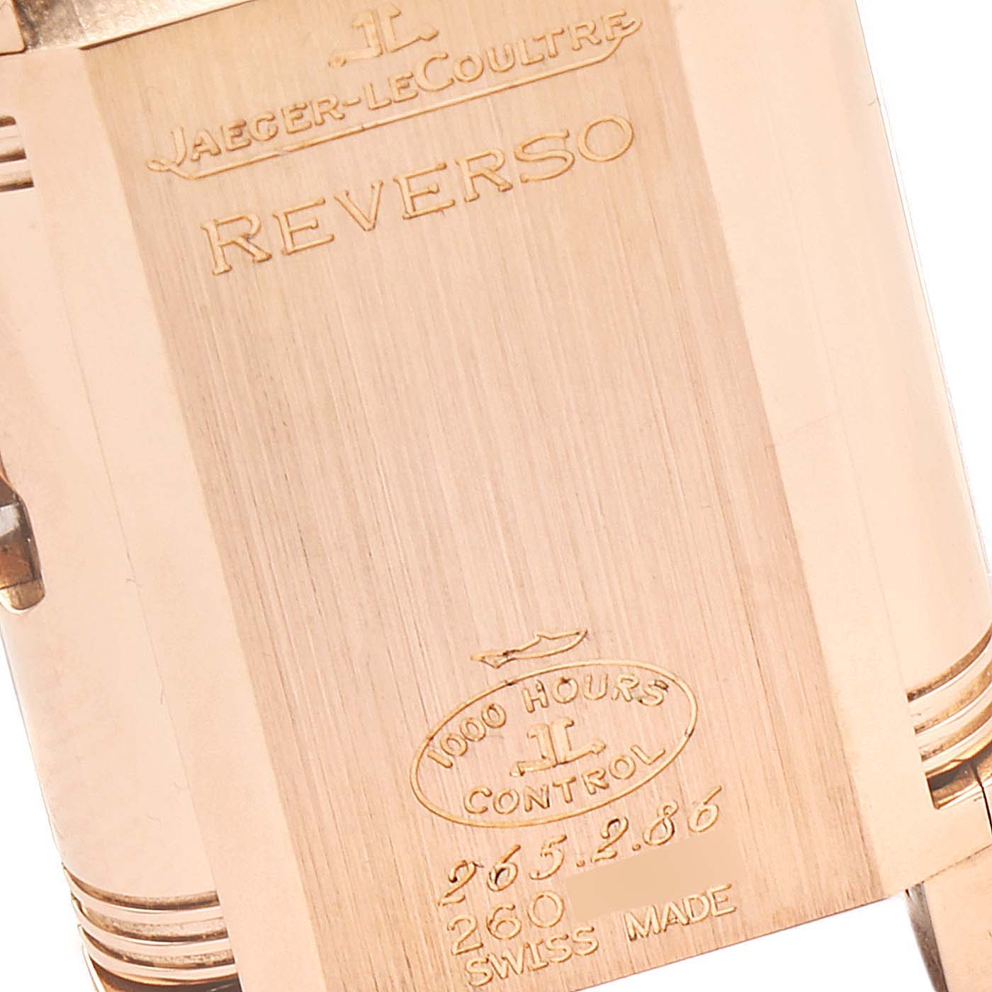 The image shows the back of a Jaeger-LeCoultre Reverso watch with engraved details and model information.