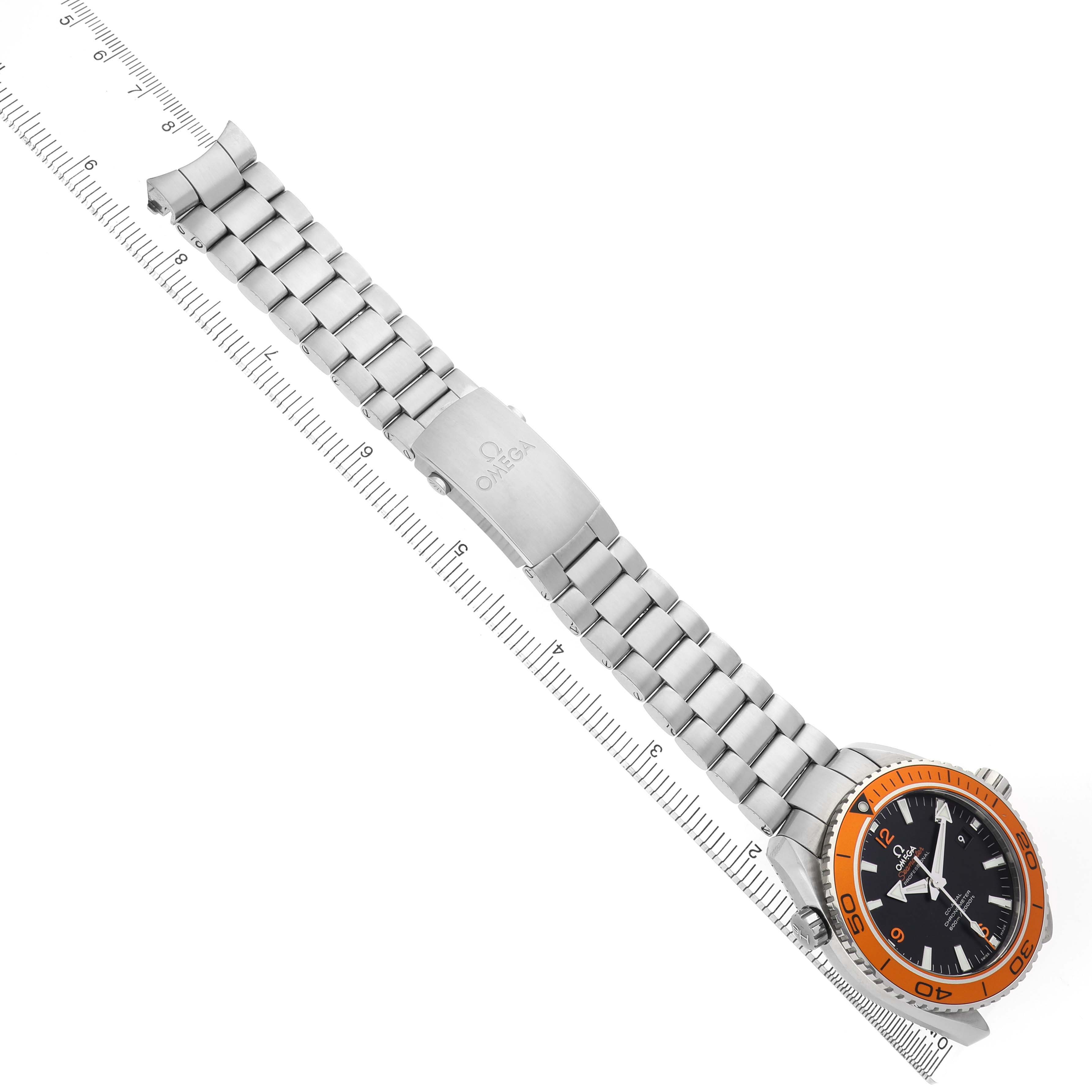 The Omega Planet Ocean 232.30.46.21.01.002 Men's Stainless Steel Black Dial watch is shown at an angle displaying the full bracelet beside a ruler, highlighting the clasp and orange bezel.
