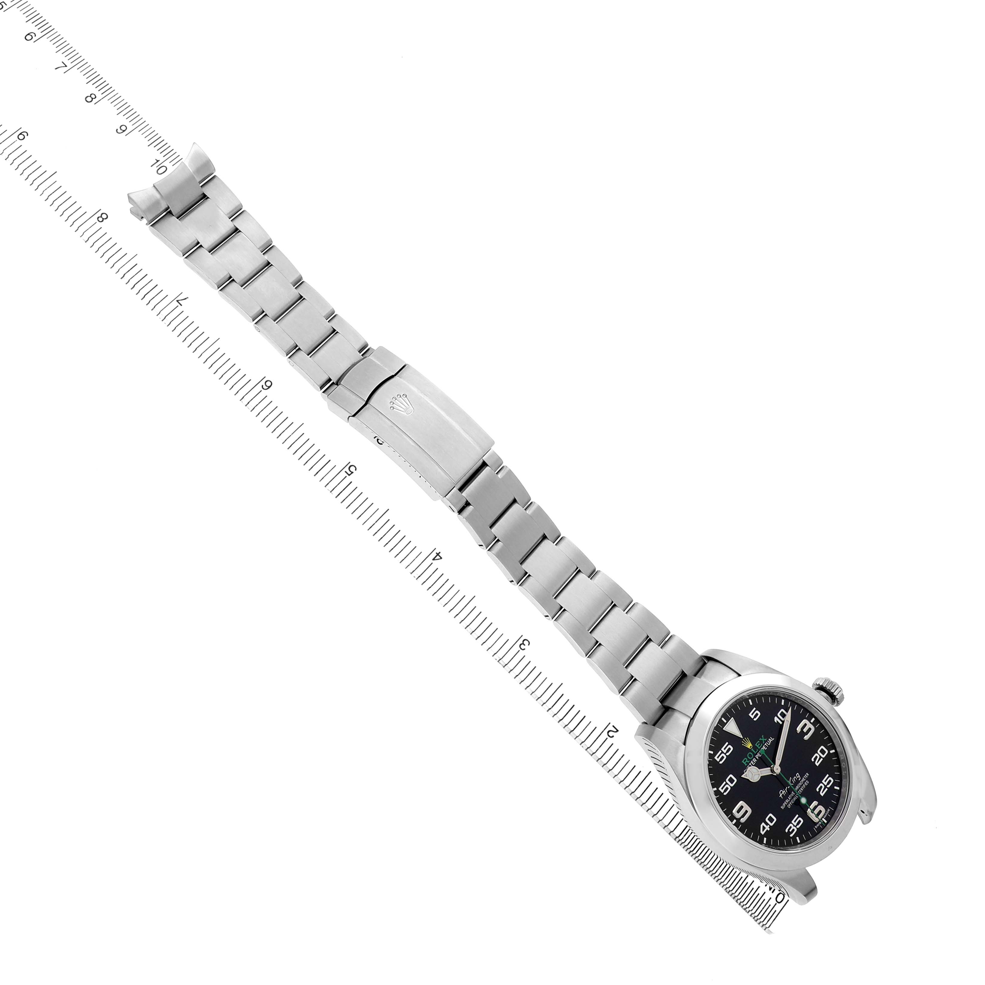 The Rolex Air-King 116900 Men's Stainless Steel Black Dial watch is shown at a top angle, displaying the bracelet, clasp, and face alongside a ruler.