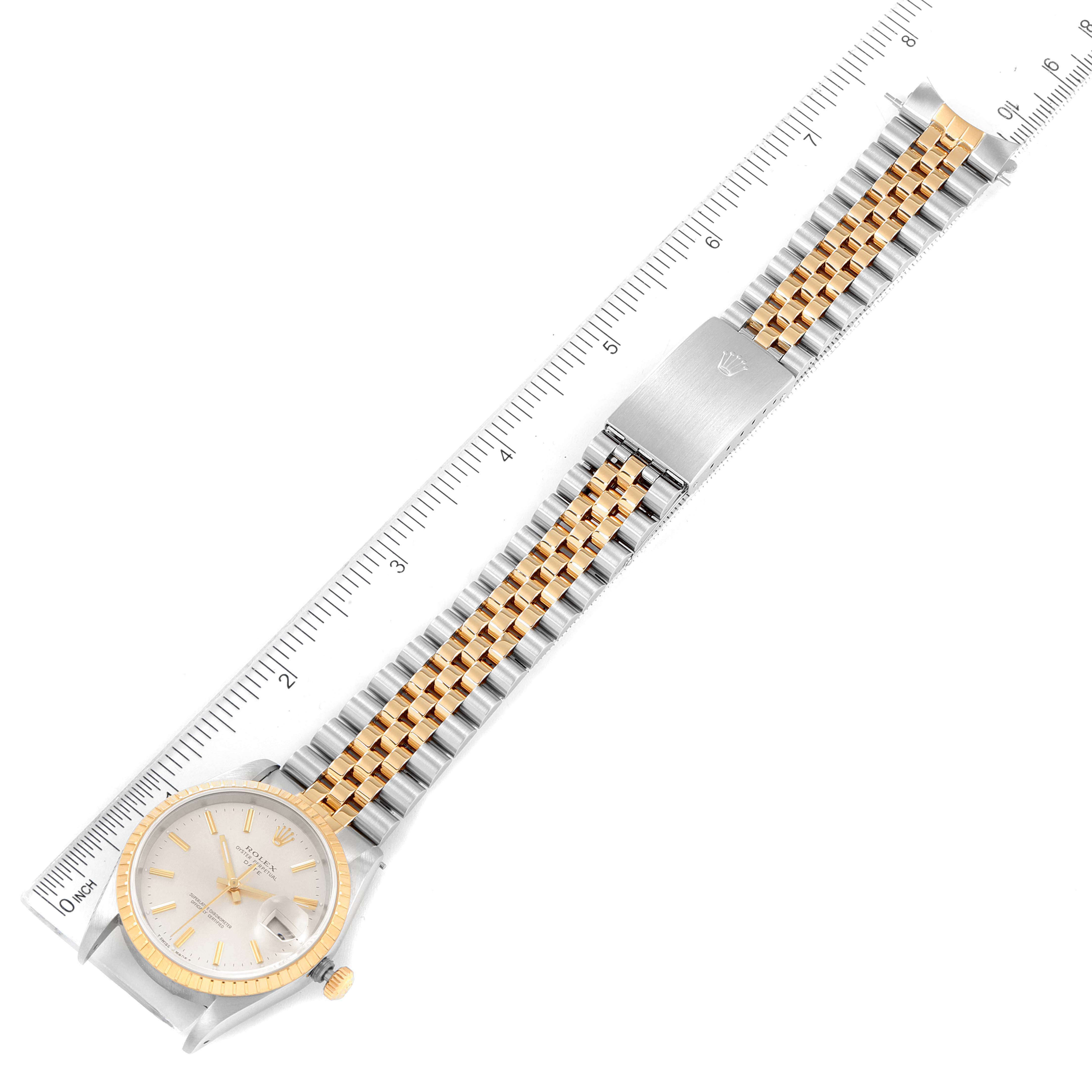 The image shows a top-down view of a Rolex Date 15223 Men's Steel and Gold (two tone) Silver Dial 15223 Men's Steel and Gold (two tone) Silver Dial model watch, including the face, band, and clasp against a ruler.