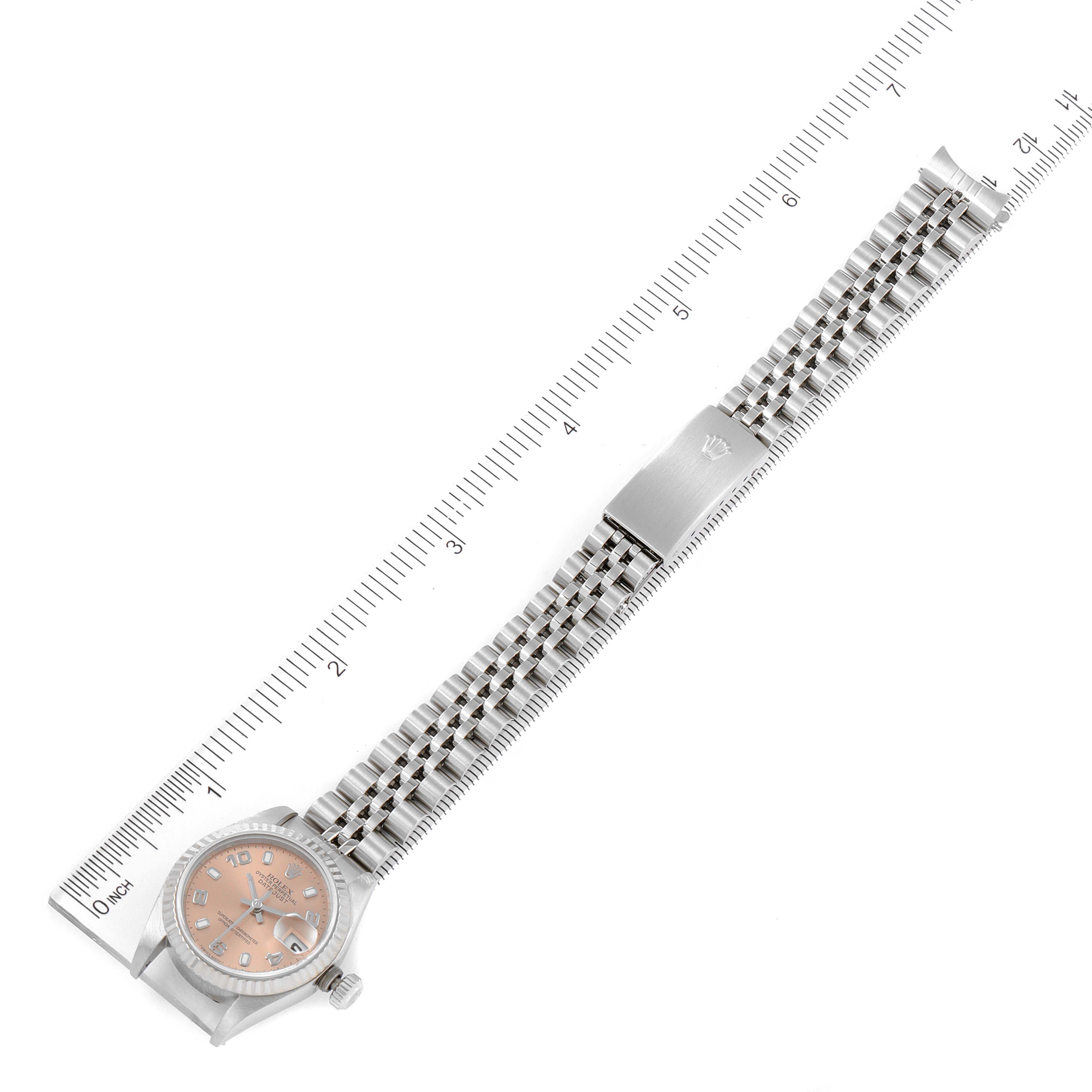 The image shows a top-down view of a Rolex Datejust 79174 Women's Stainless Steel Pink Dial 79174 Women's Stainless Steel Pink Dial watch, featuring the face, bracelet, and clasp next to a ruler for size reference.