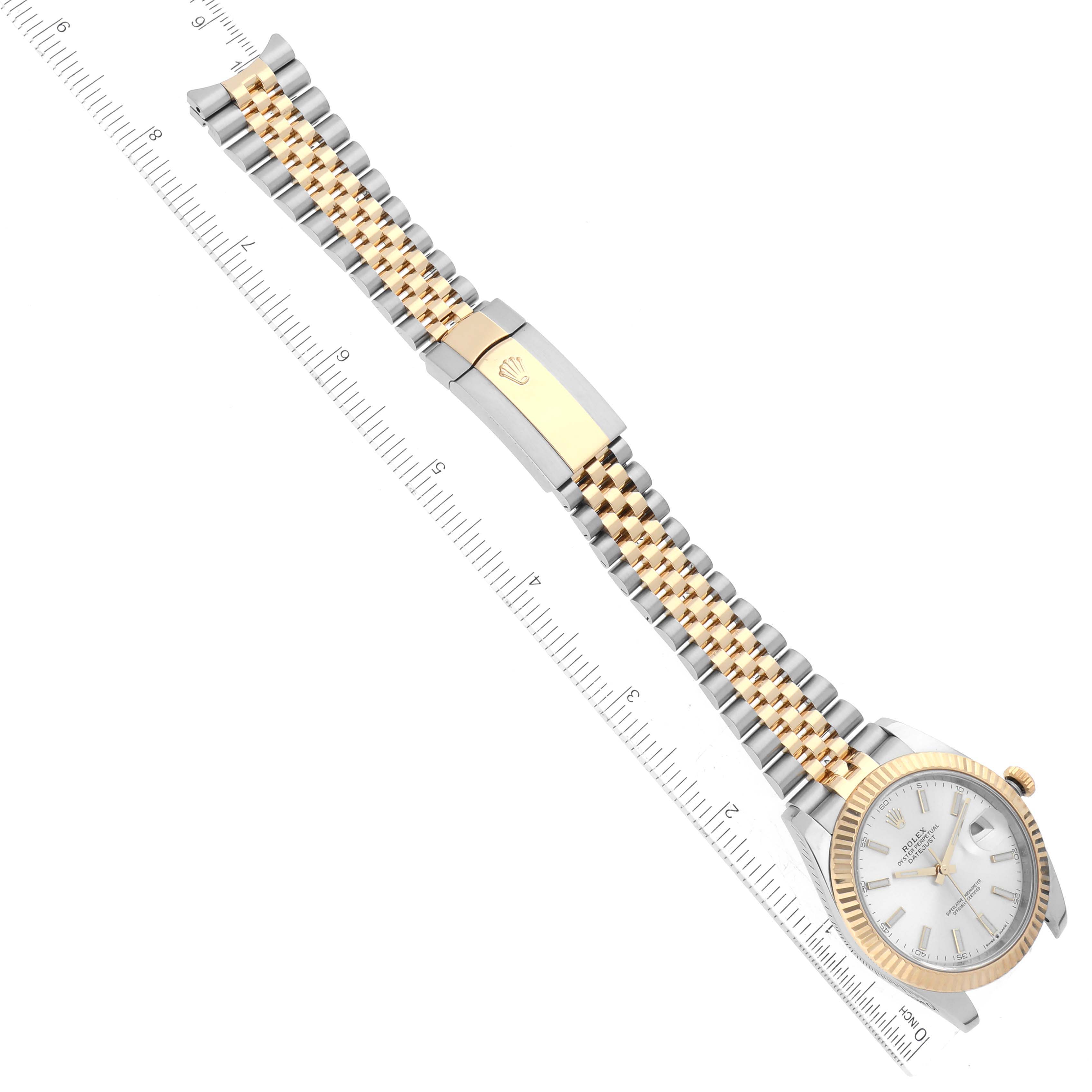 This image shows a Rolex Datejust 41 126333 Men's Steel and Gold (two tone) Silver Dial 126333 Men's Steel and Gold (two tone) Silver Dial watch taken from a top-down angle, highlighting its band and clasp against a ruler for scale.
