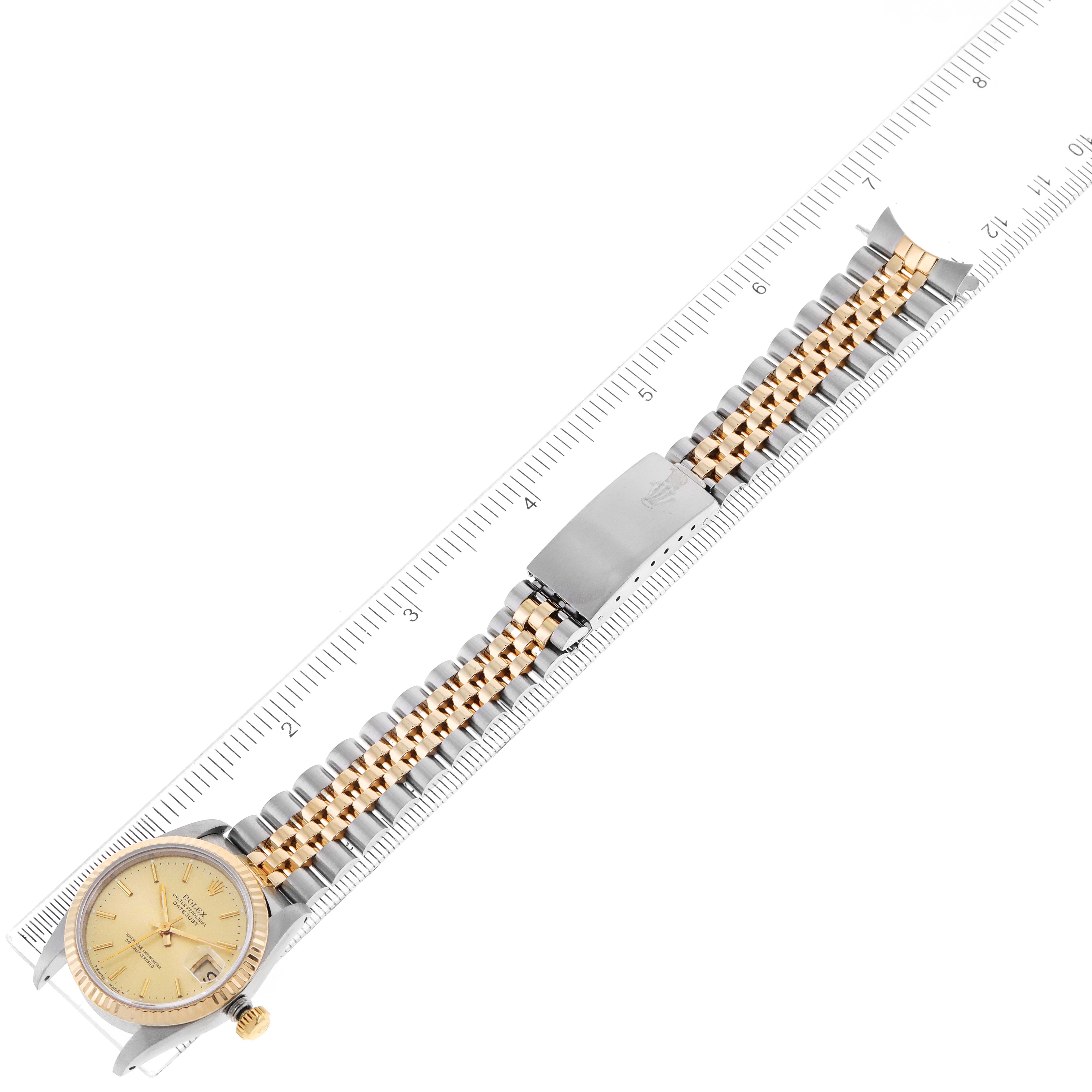 The image shows a full view of a Rolex Mid-Size 68273 Women's Steel and Gold (two tone) Champagne Dial 68273 Women's Steel and Gold (two tone) Champagne Dial model watch laid flat alongside a ruler.