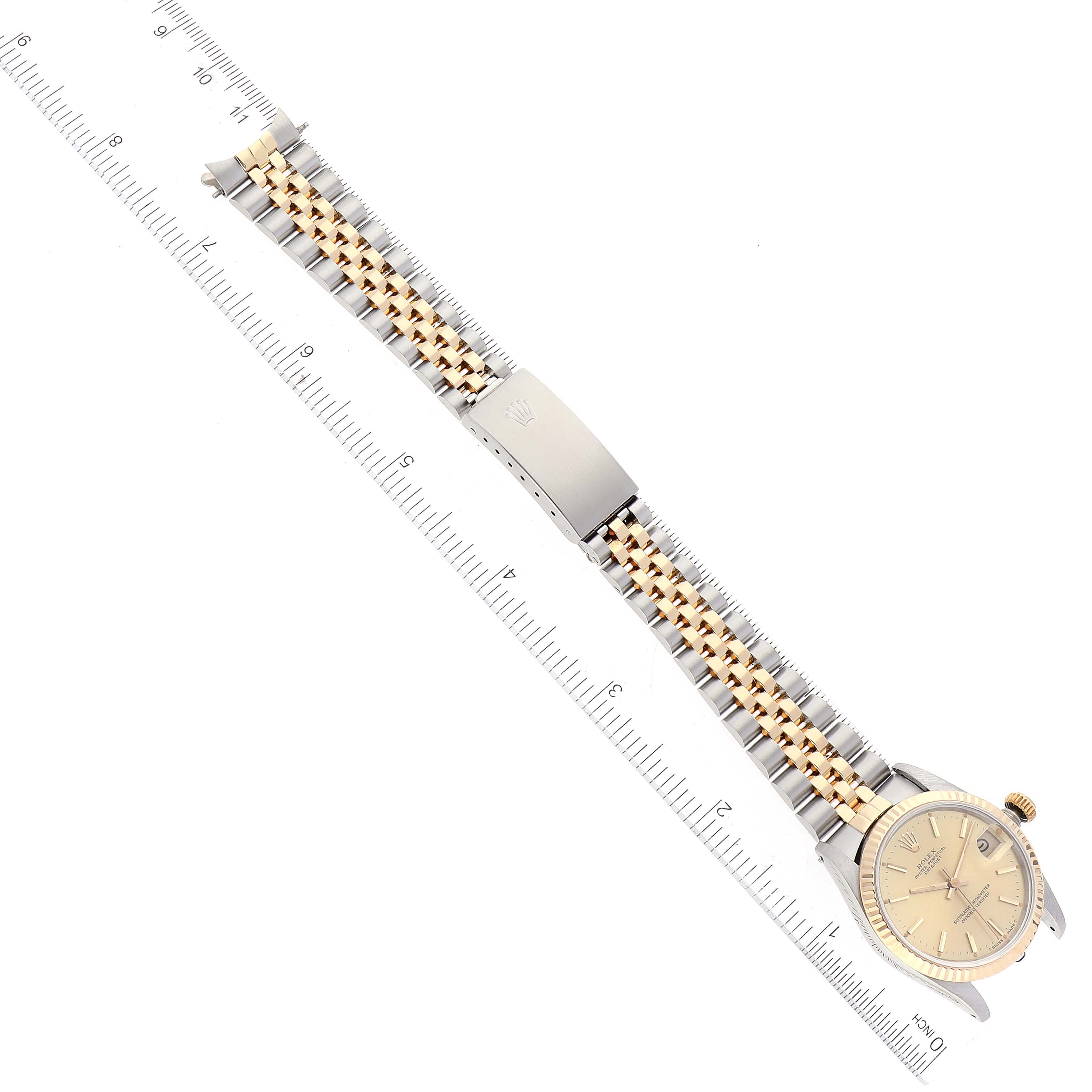 The image shows a top view of a Rolex Mid-Size 68273 Women's Steel and Gold (two tone) Champagne Dial 68273 Women's Steel and Gold (two tone) Champagne Dial model watch with its bracelet and clasp fully extended against a ruler.