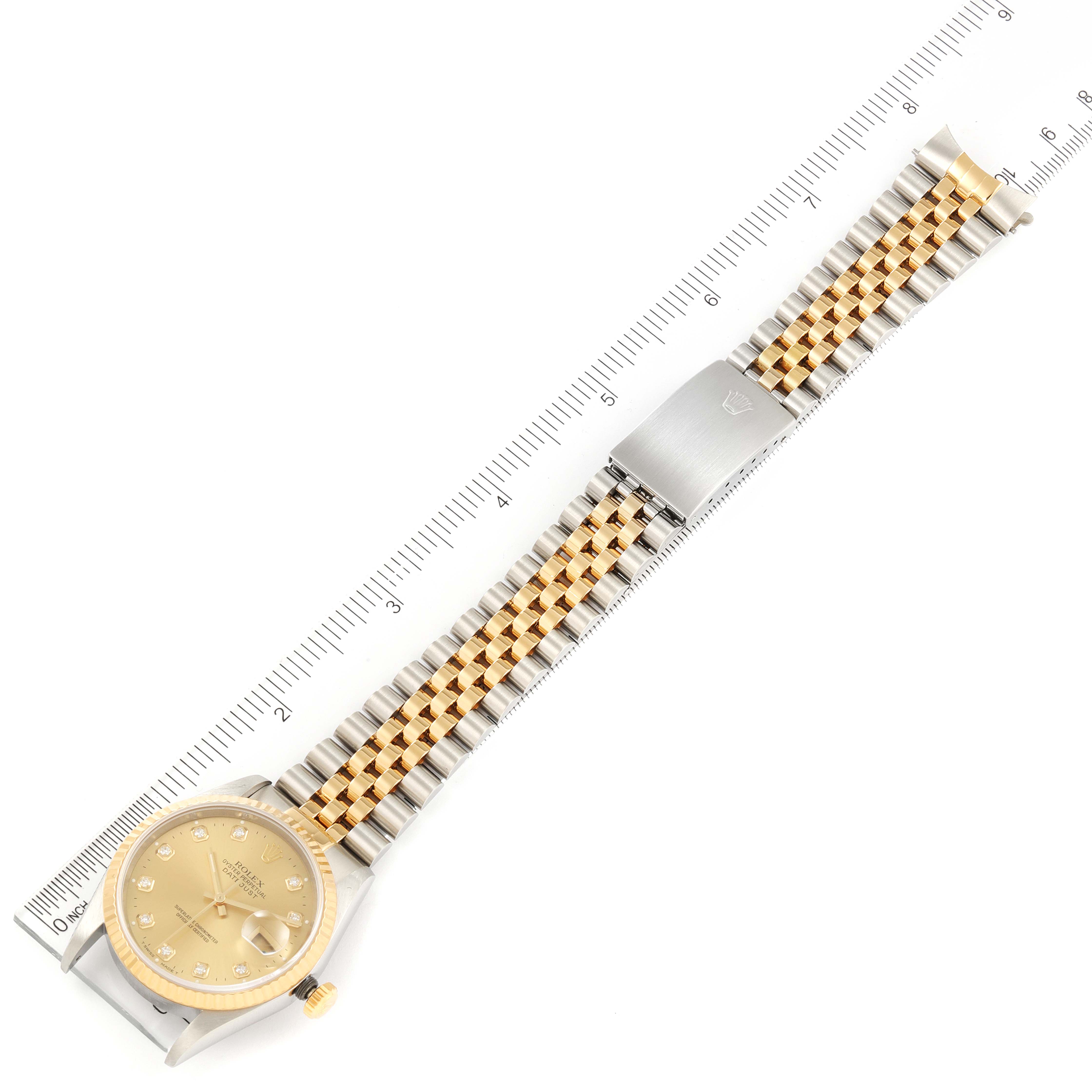 The image shows a Rolex Datejust 16233 Men
s Steel and Gold (two tone) Champagne Dial 16233 Men
s Steel and Gold (two tone) Champagne Dial watch positioned horizontally, showcasing the dial, bezel, and jubilee bracelet alongside a ruler for scale.
