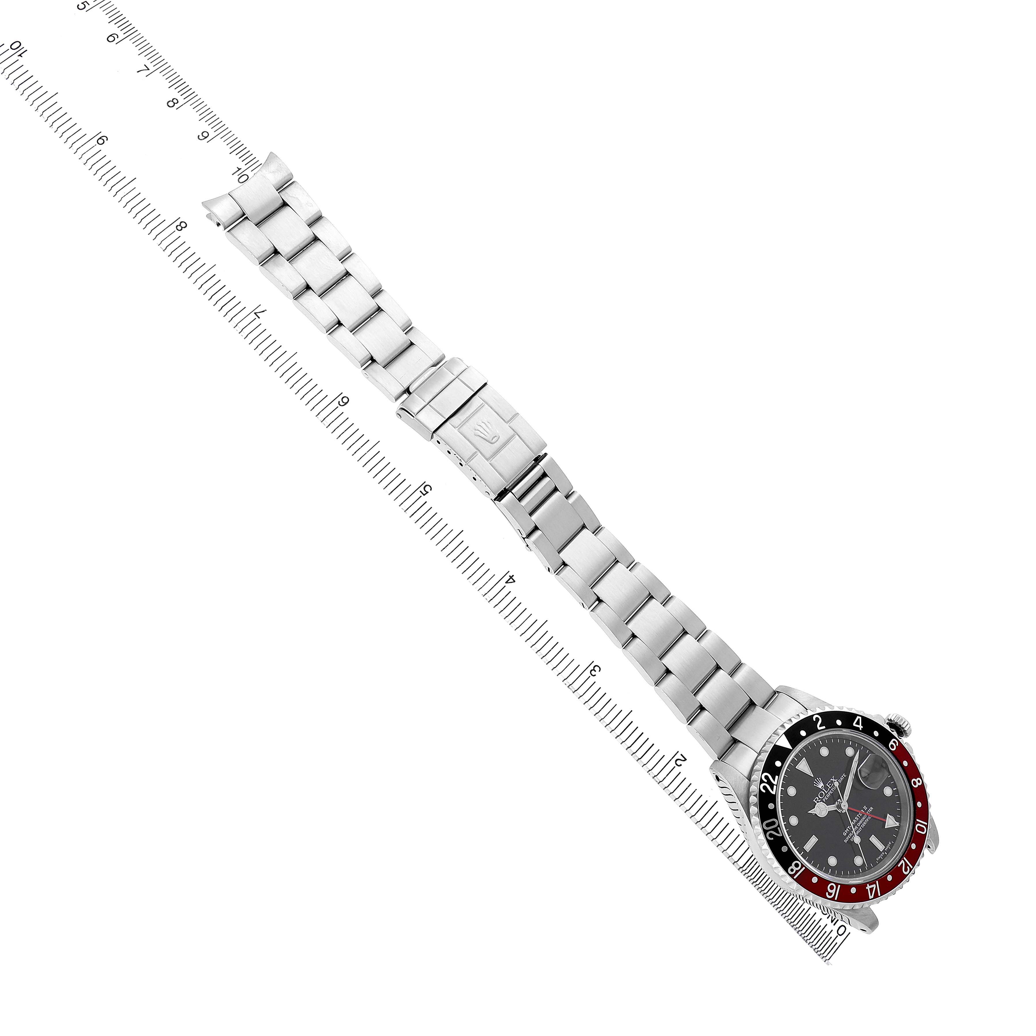 The Rolex GMT-Master 16710 Men's Stainless Steel Black Dial watch is shown from a top-down angle, highlighting the bezel, dial, bracelet, and clasp near a ruler.