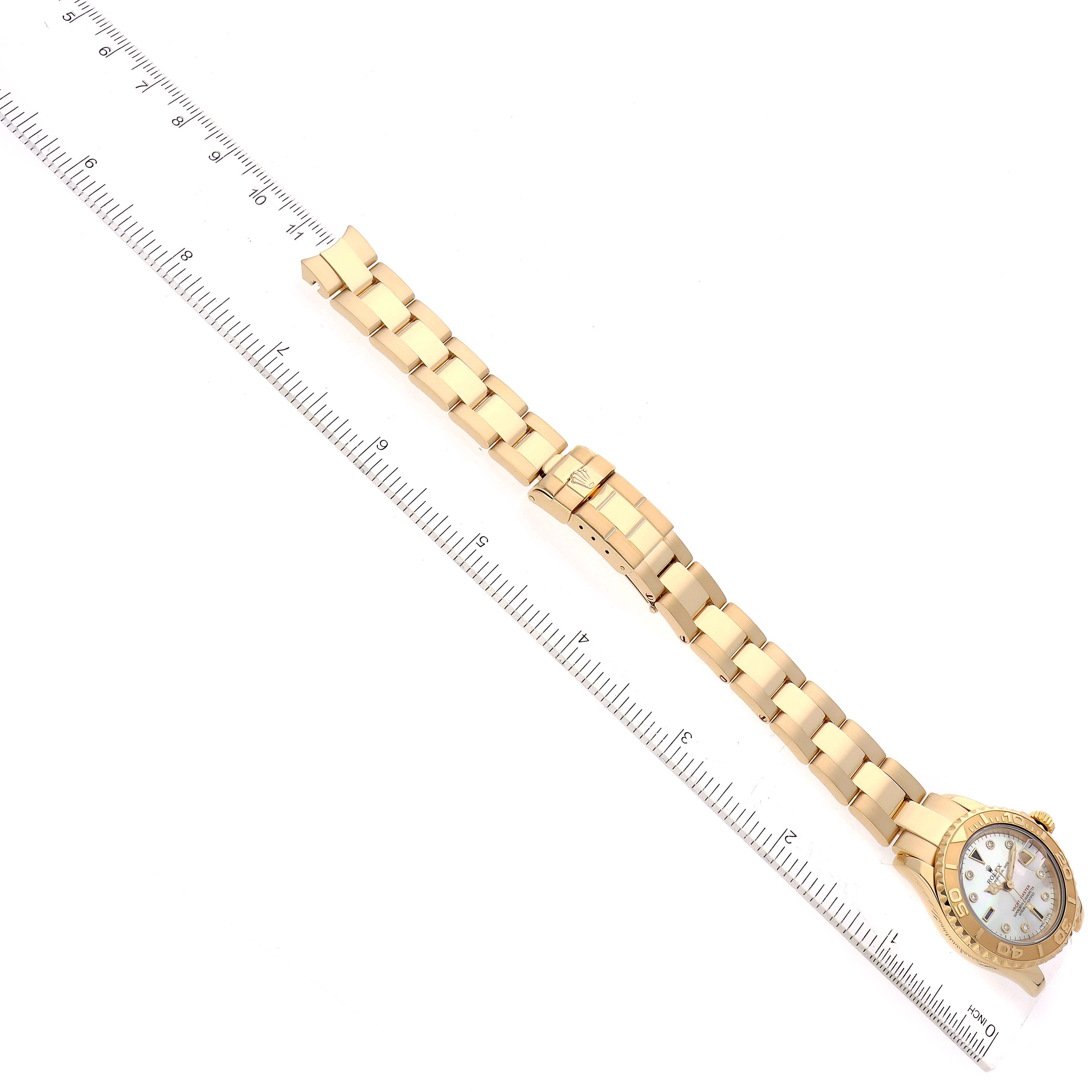 The Rolex Yacht-Master 69628 Women's Yellow Gold Mother of Pearl Dial 69628 Women's Yellow Gold Mother of Pearl Dial watch is shown flat from above, with its full bracelet and clasp extended next to a ruler.