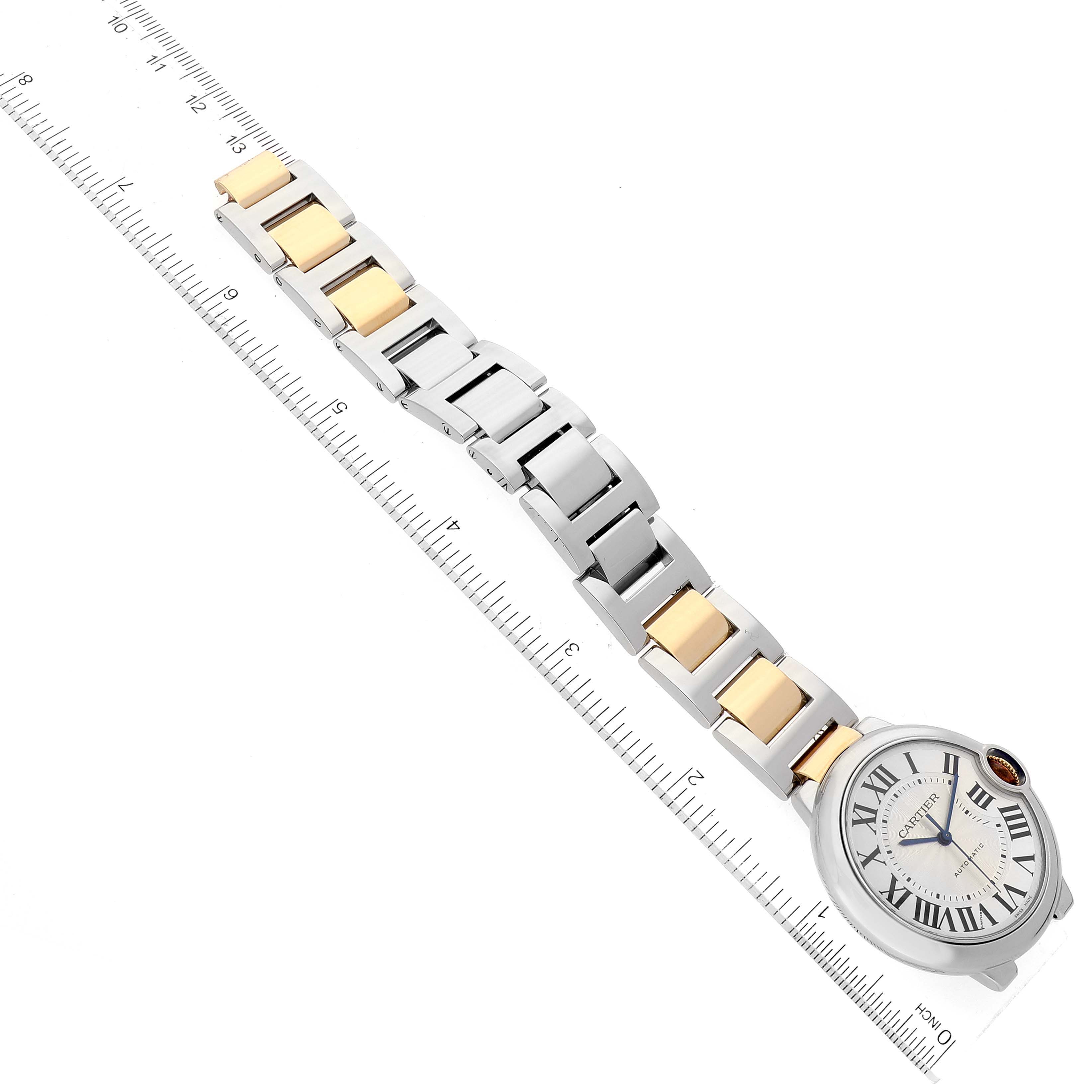 The image shows a top-down view of a Cartier Ballon Bleu W2BB0012 Men
s Steel and Gold (two tone) Silver Dial W2BB0012 Men
s Steel and Gold (two tone) Silver Dial watch placed alongside a ruler for size reference.