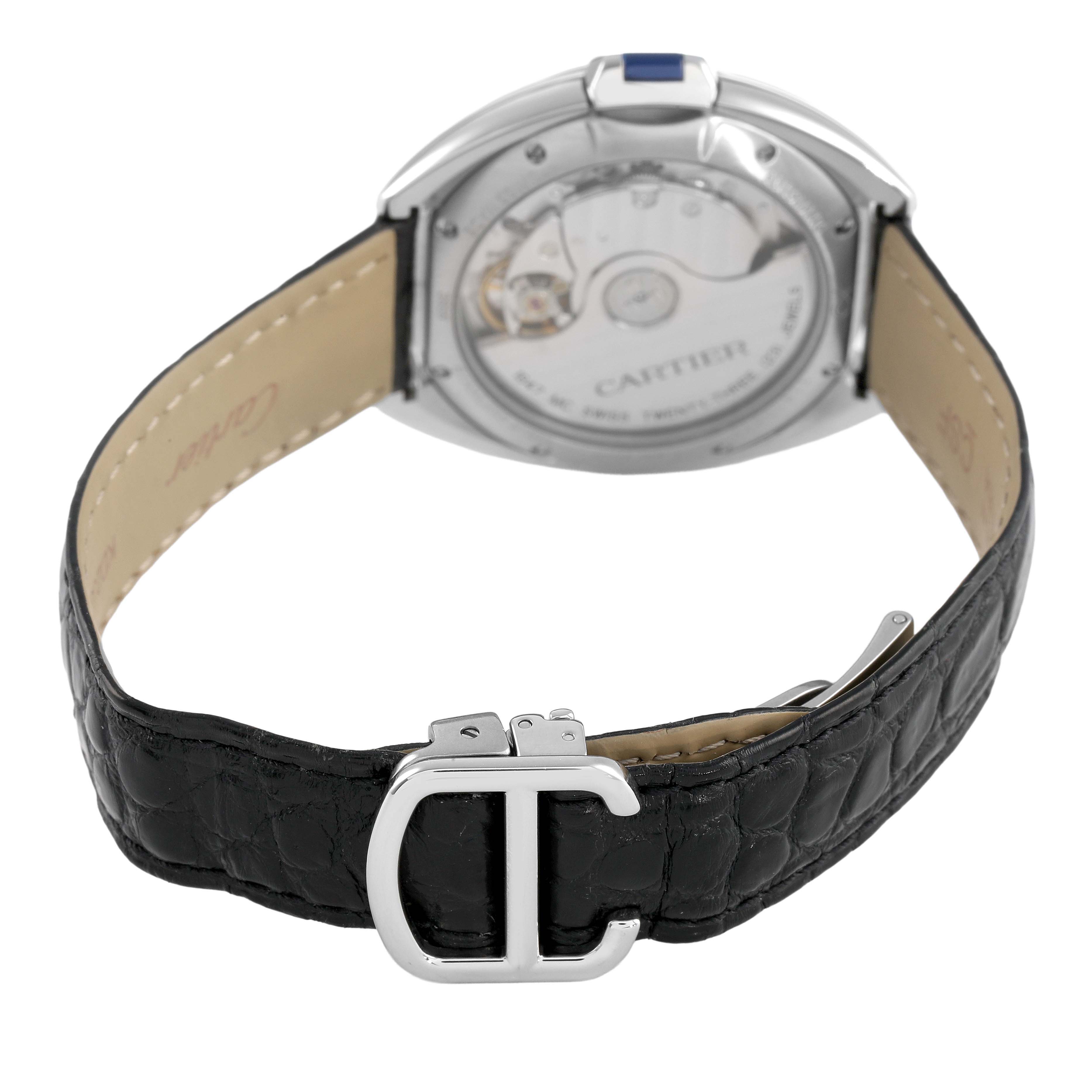 The Cartier Clé watch is shown from the back, highlighting the open case back and black leather strap with a "C" buckle.