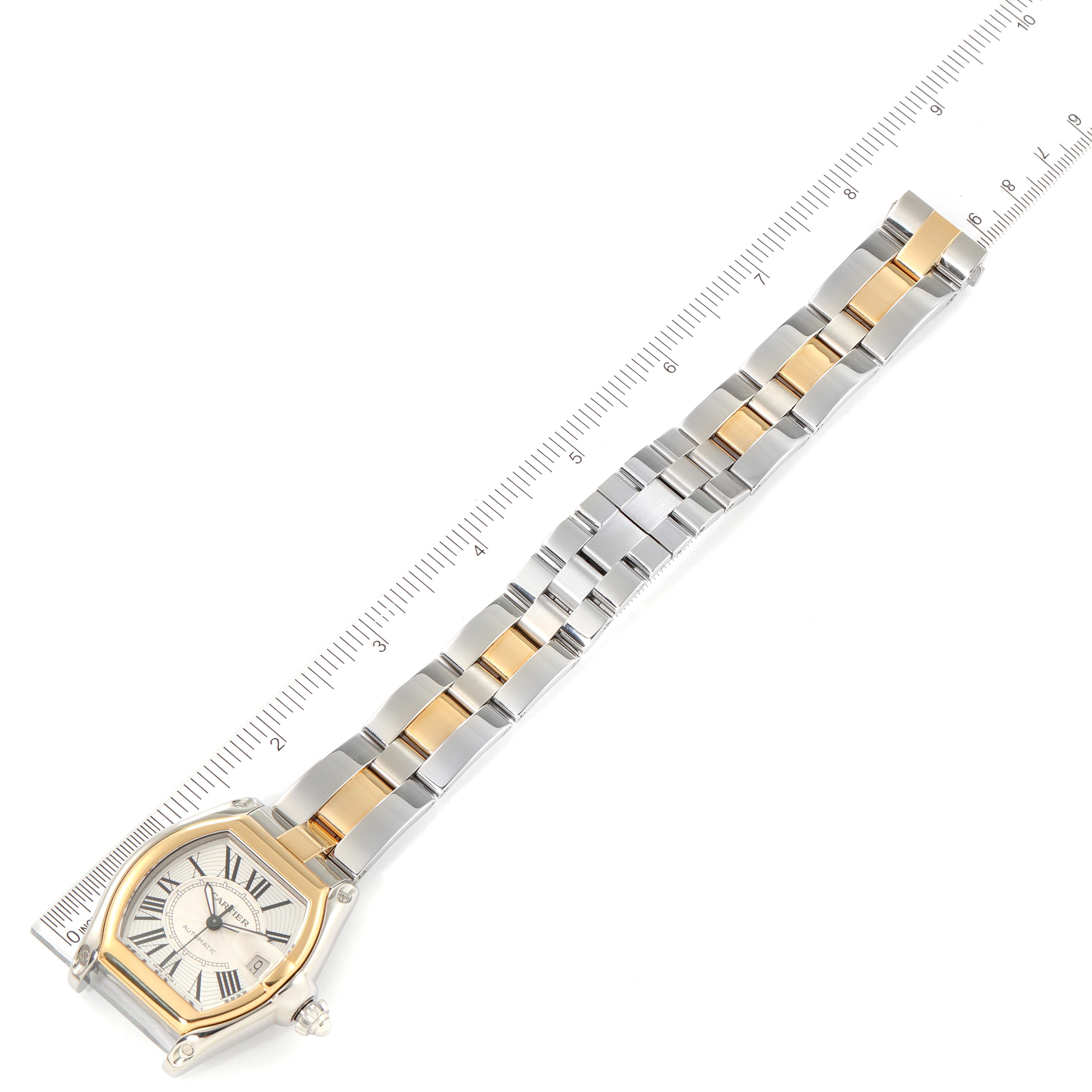 The Cartier Roadster W62031Y4 Men
s Steel and Gold (two tone) Silver Dial W62031Y4 Men
s Steel and Gold (two tone) Silver Dial watch is shown from a top-down angle, displaying its face, bezel, and full bracelet next to a ruler for scale.