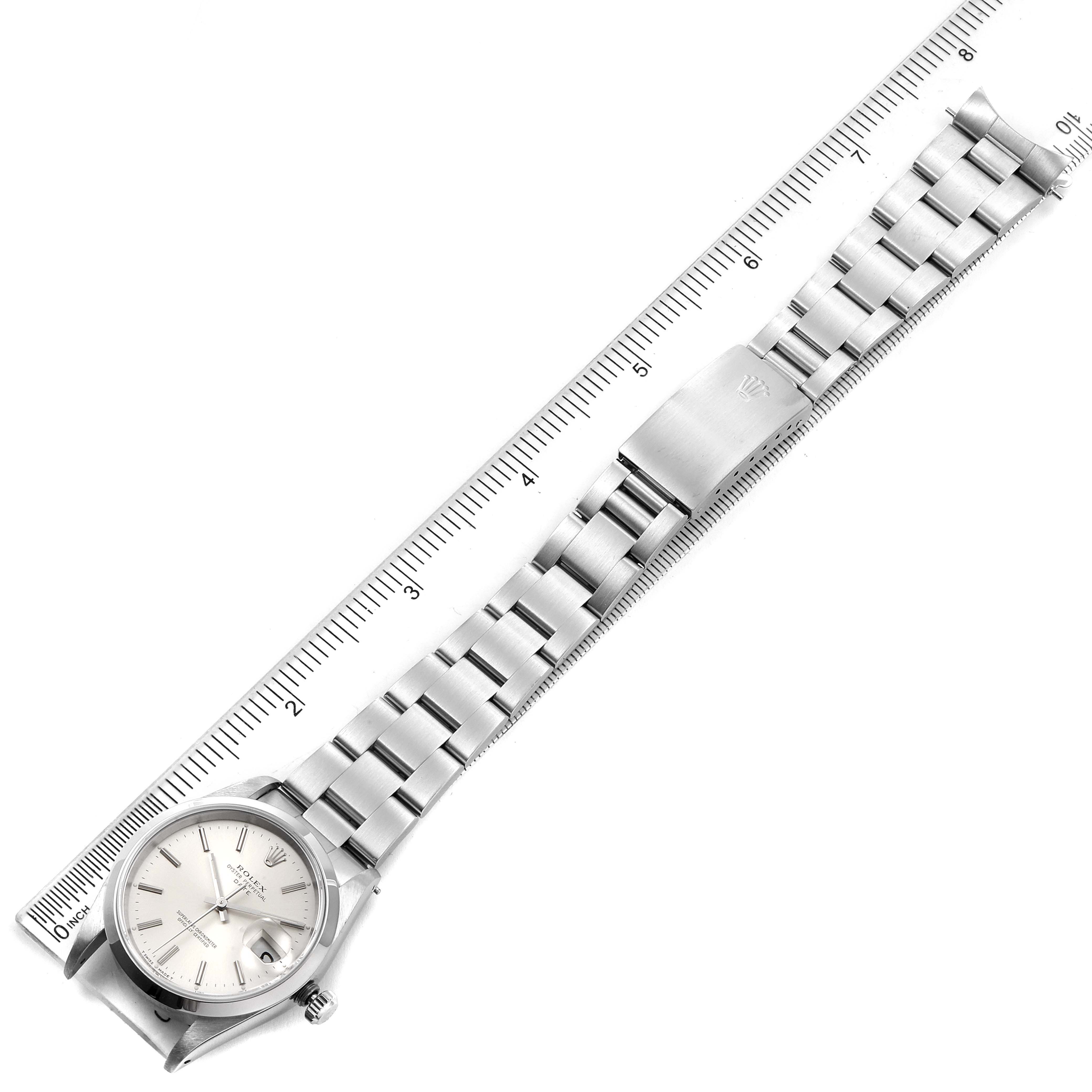 The Rolex Date 15200 Men's Stainless Steel Silver Dial 15200 Men's Stainless Steel Silver Dial model watch is shown from a top-down angle, featuring the face, bracelet, clasp, and part of a measuring ruler.