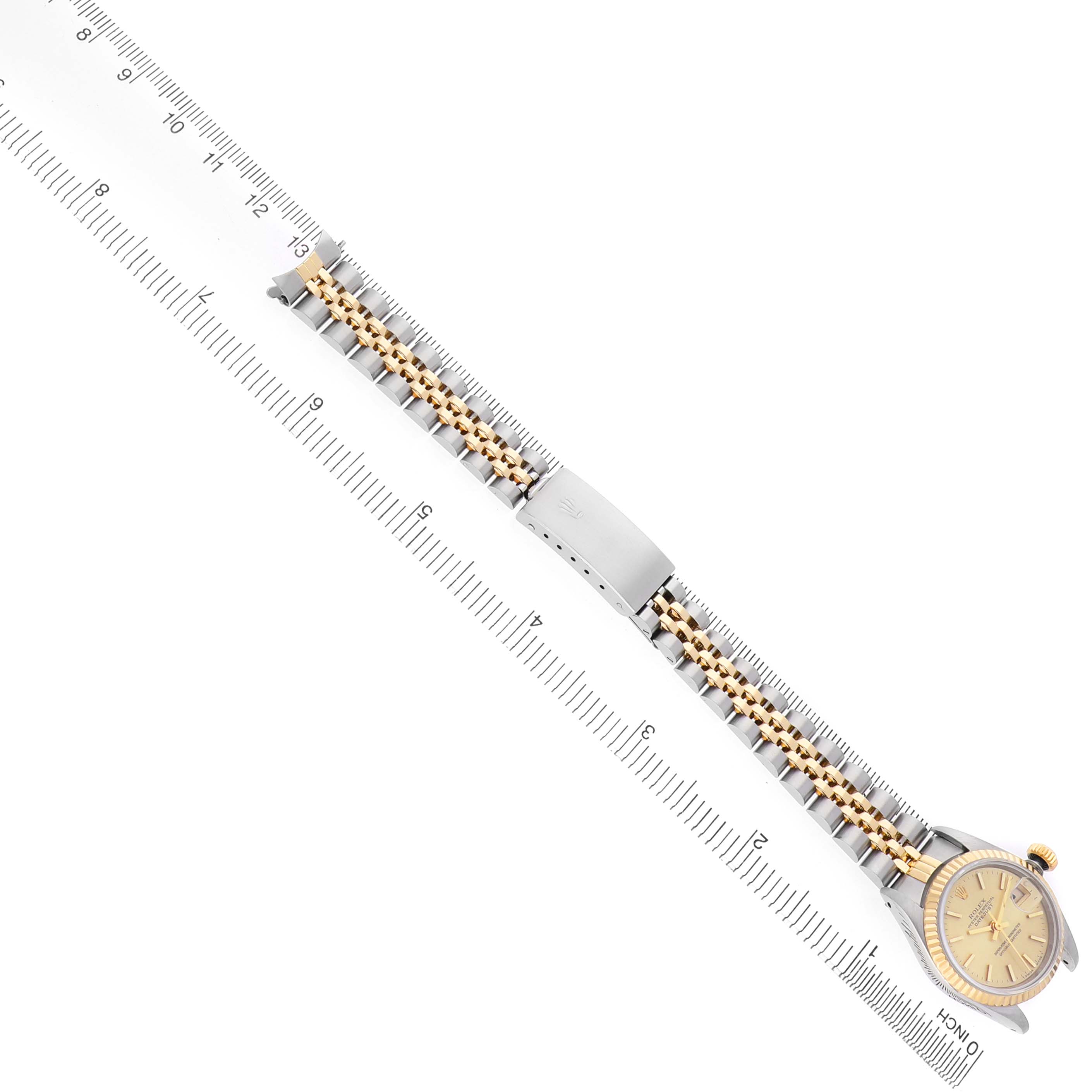 The Rolex Datejust 69173 Women's Steel and Gold (two tone) Champagne Dial watch is shown at an angle, highlighting the full bracelet and face alongside a measuring scale.