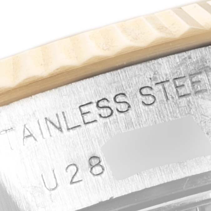 This close-up angle of the Rolex Datejust 69173 Women
s Steel and Gold (two tone) Champagne Dial 69173 Women
s Steel and Gold (two tone) Champagne Dial watch shows the fluted bezel and part of the engraved stainless steel case with text.