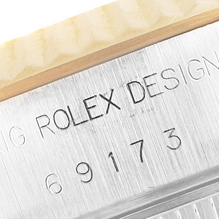 The image shows a close-up view of the engraved serial number and "Rolex Design" on the case of a Rolex Datejust 69173 Women
s Steel and Gold (two tone) Champagne Dial 69173 Women
s Steel and Gold (two tone) Champagne Dial watch.