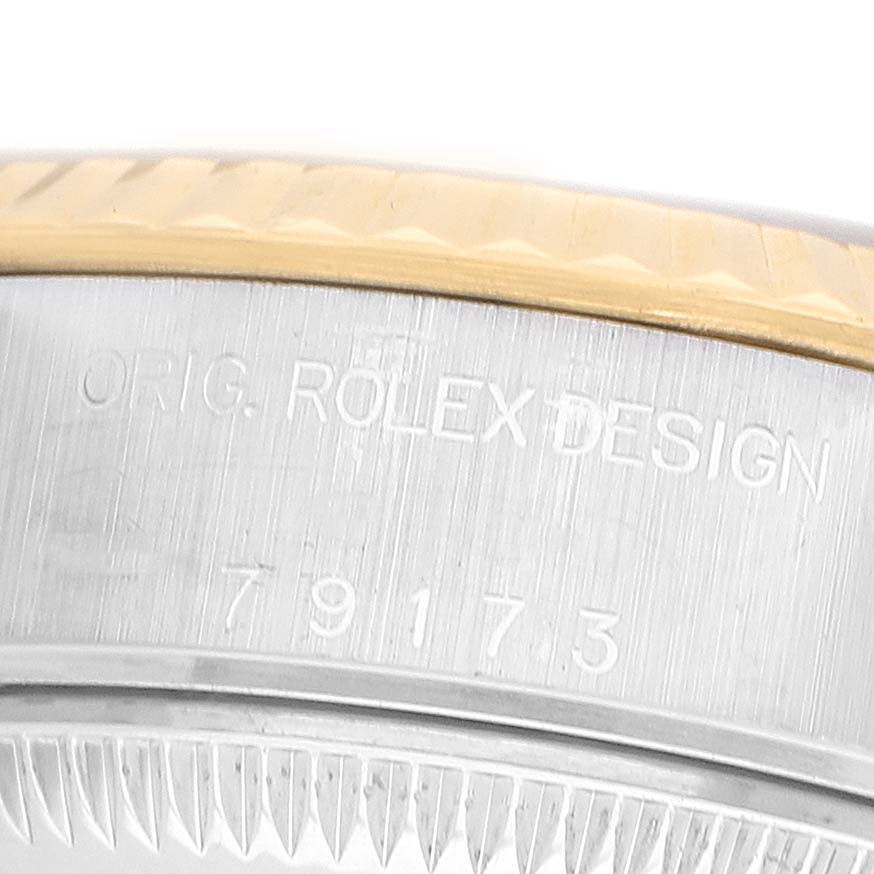 The image shows a close-up of the edge of a Rolex Datejust 79173 Women's Steel and Gold (two tone) Champagne Dial watch's bezel and case, featuring engravings.