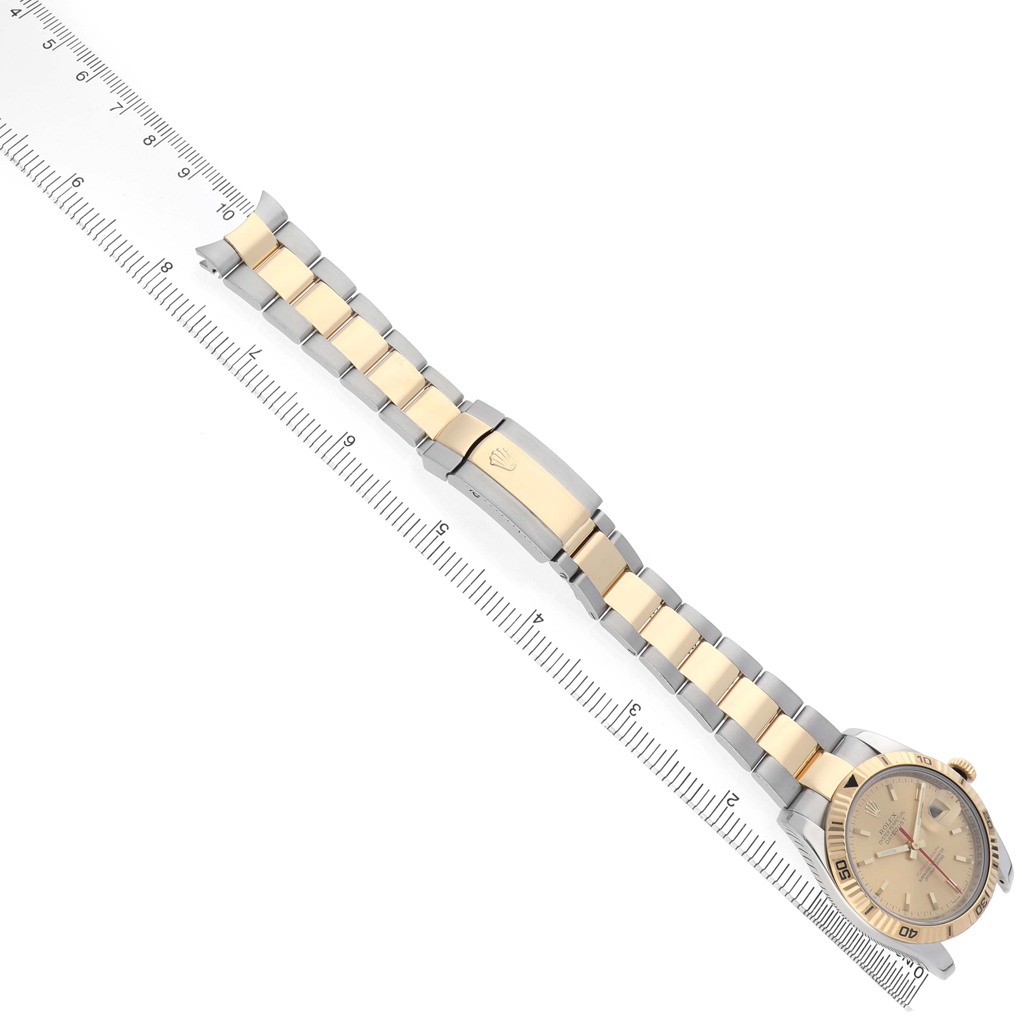 The image shows the Rolex Turn-o-Graph 116263 Men's Steel and Gold (two tone) Champagne Dial watch at an overhead angle with its bracelet and clasp extended along a ruler.