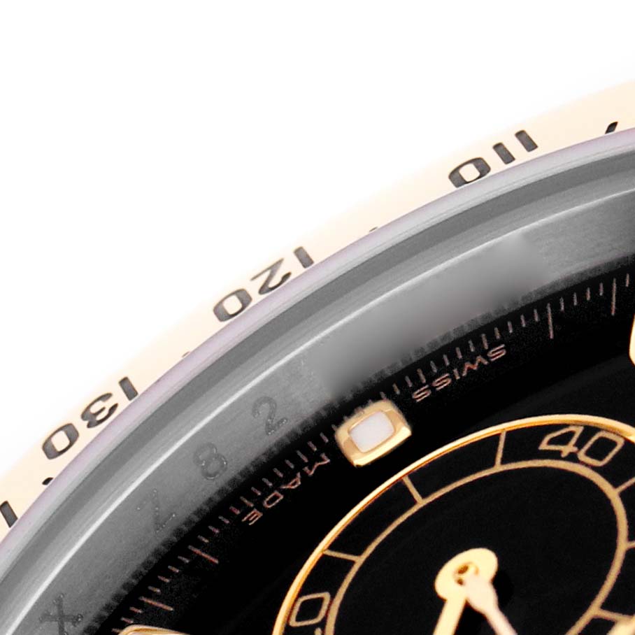 The image shows a close-up of the bezel and part of the dial of a Rolex Daytona 116523 Men's Steel and Gold (two tone) Black Dial watch, focusing on the tachymetric scale.