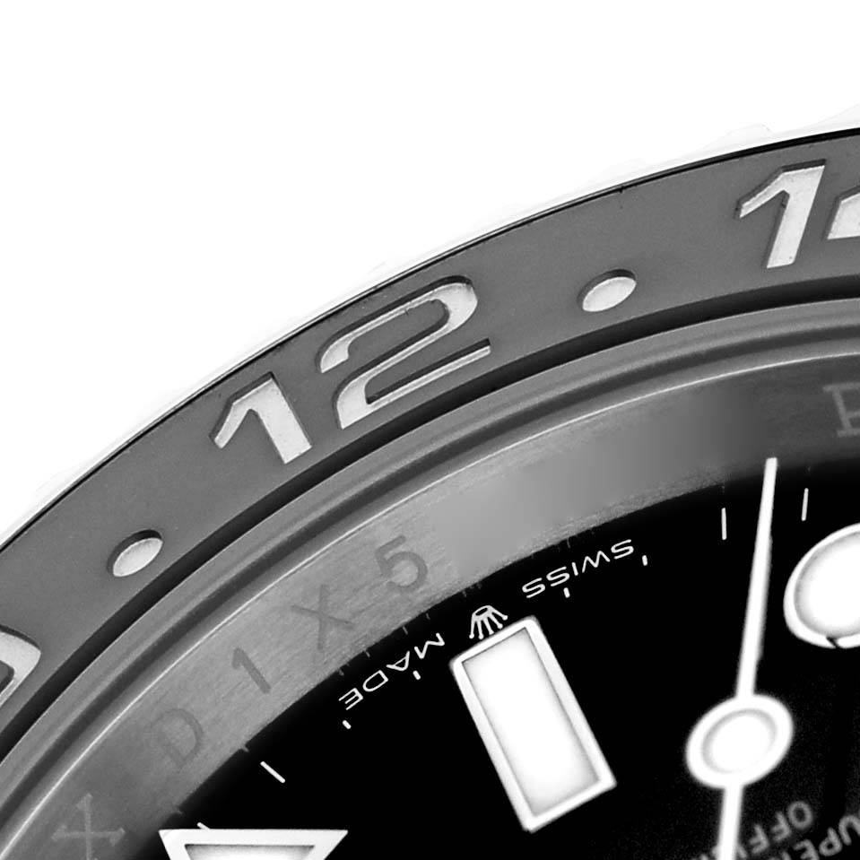 The image shows a close-up of the bezel and part of the dial of a Rolex GMT-Master 126710GRNR Men's Stainless Steel Black Dial, highlighting the "12" on the bezel.
