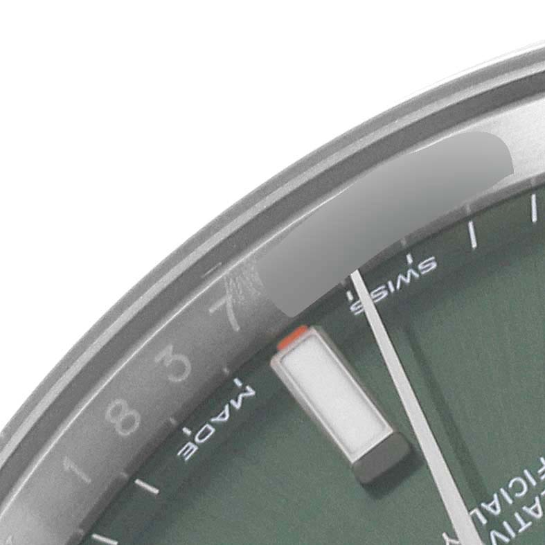 The close-up image of the Rolex Oyster Perpetual 114200 Men
s Stainless Steel Green Dial 114200 Men
s Stainless Steel Green Dial watch shows a segment of the dial, specifically the markers, part of the second hand, and the inner rim.