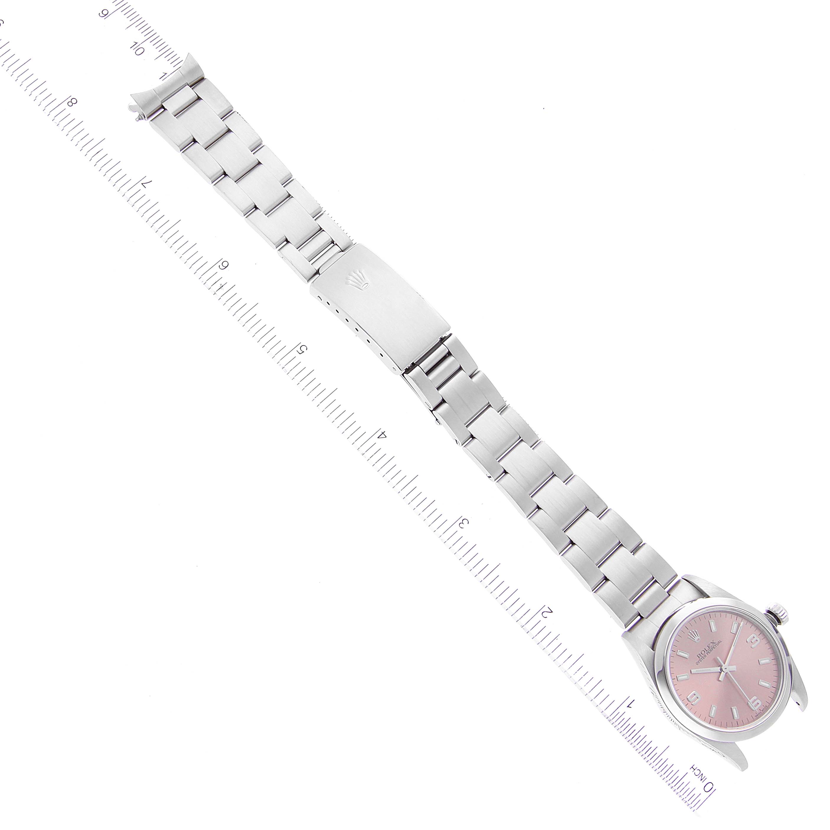 The image shows a top-down view of a Rolex Mid-Size 77080 Women
s Stainless Steel Pink Dial 77080 Women
s Stainless Steel Pink Dial watch with a pink dial, full bracelet, clasp, and adjacent rulers for scale.
