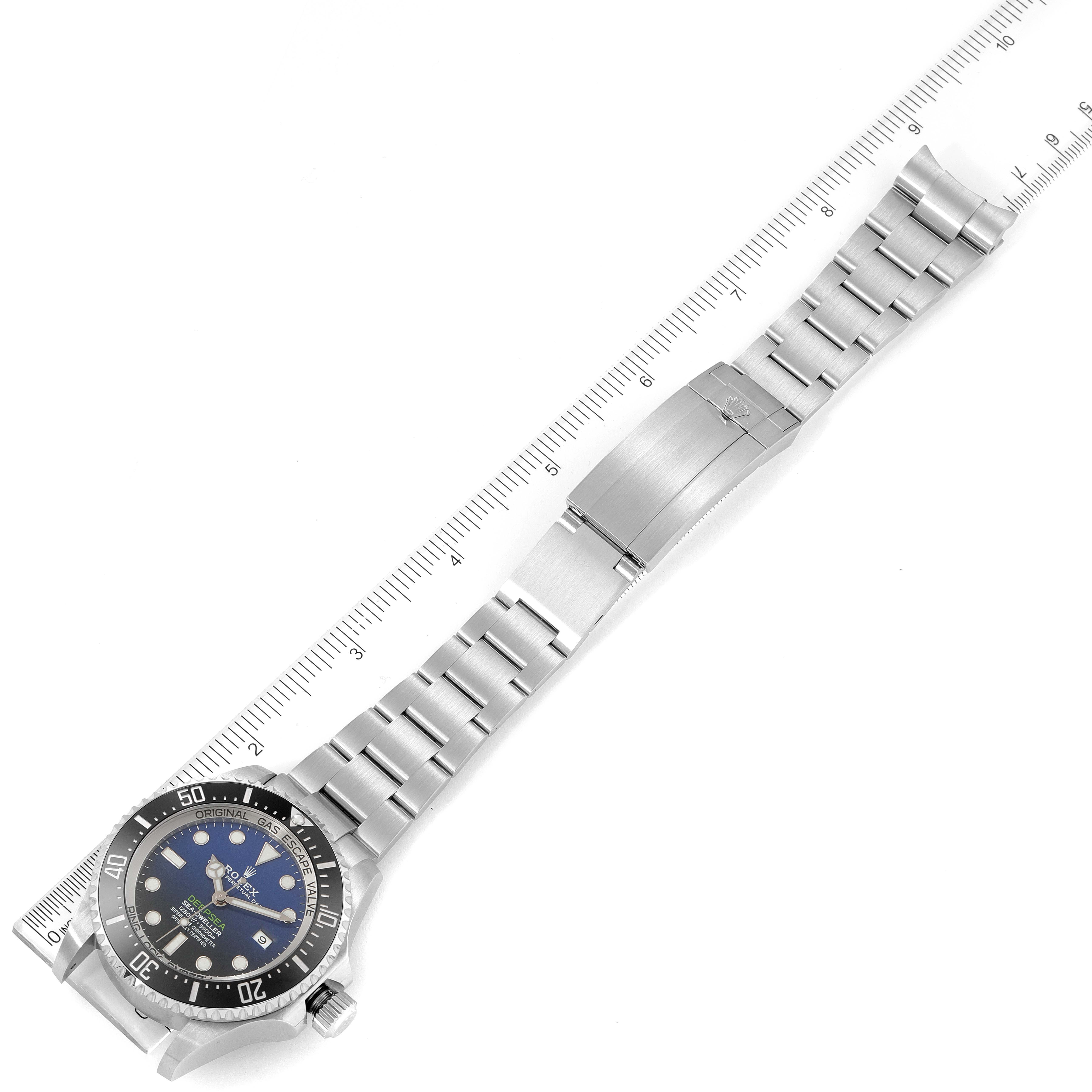 The Rolex Sea-Dweller 126660 Men's Stainless Steel Blue Dial 126660 Men's Stainless Steel Blue Dial watch is shown from a top-down angle with its full bracelet extended alongside a ruler.