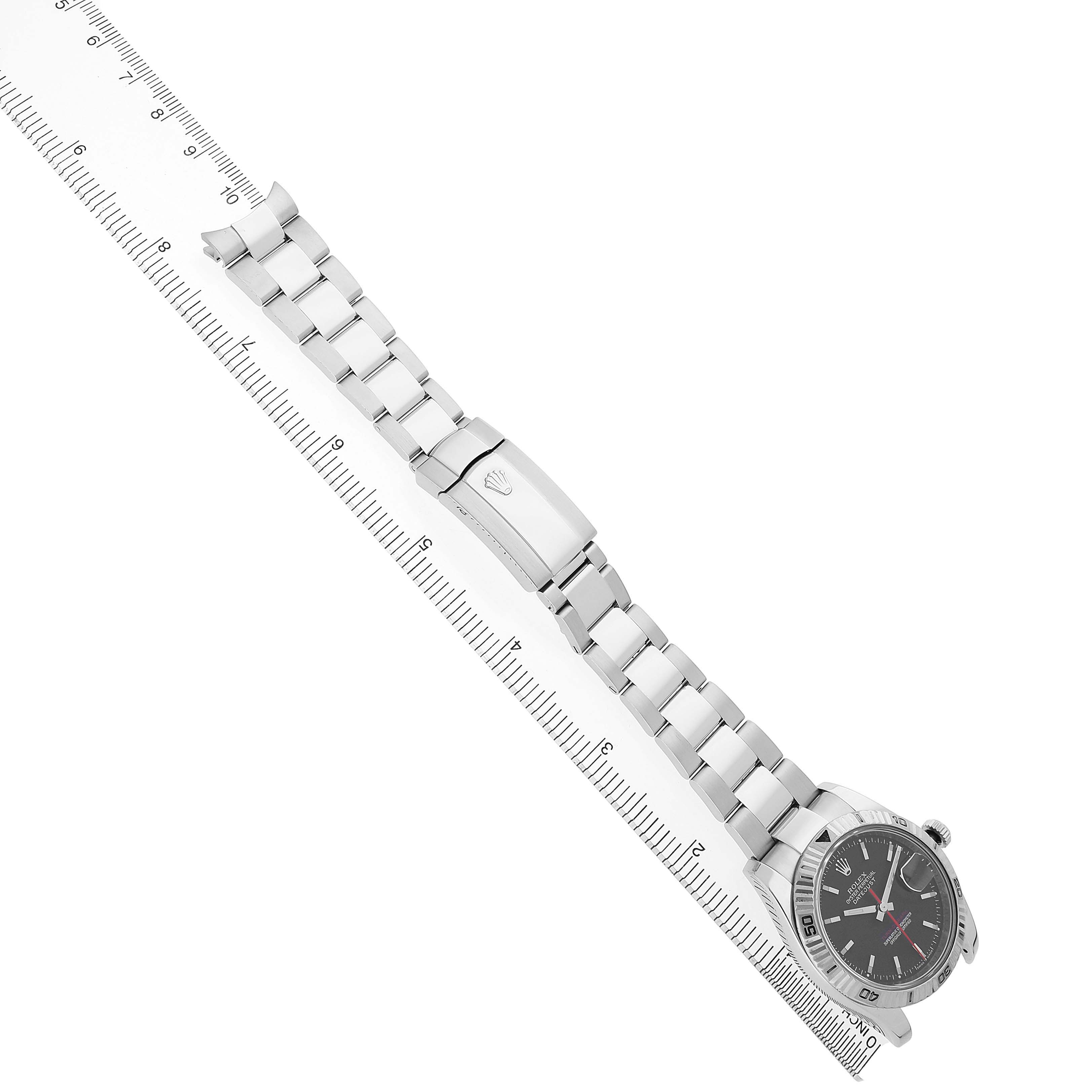 The Rolex Turn-o-Graph 116264 Men's Stainless Steel Black Dial watch is shown at an angled view, highlighting the full bracelet and clasp alongside a ruler for scale.