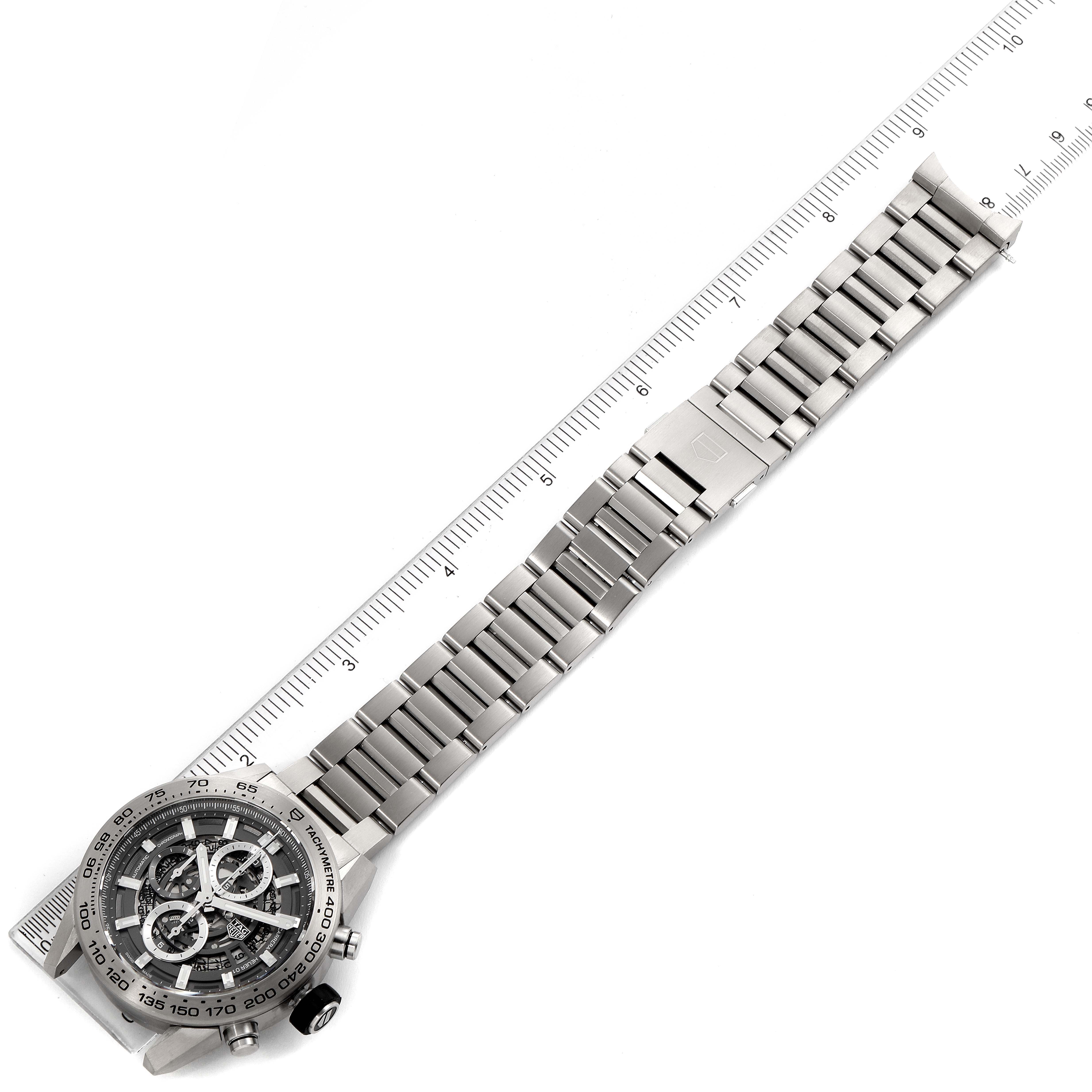 The Tag Heuer Carrera CAR2A8A.FT6072 Men's Titanium Grey Dial CAR2A8A.FT6072 Men's Titanium Grey Dial watch is shown from an overhead angle, displaying its face, metal bracelet, and buckle alongside a ruler.