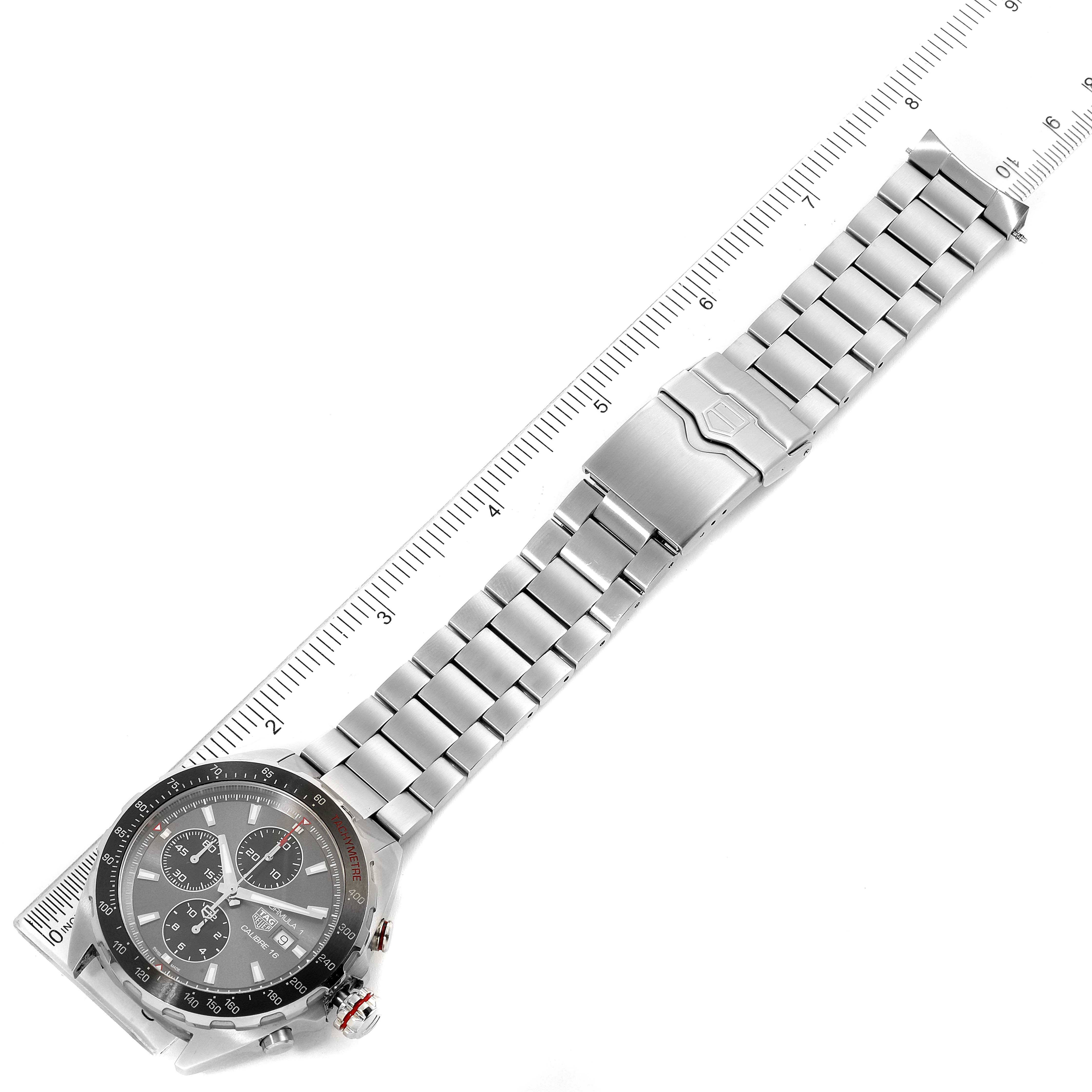 The image shows a Tag Heuer Formula 1 CAZ2012.BA0970 Men's Stainless Steel Grey Dial CAZ2012.BA0970 Men's Stainless Steel Grey Dial watch laid flat, showcasing the face, bezel, strap, and clasp alongside a measuring ruler.