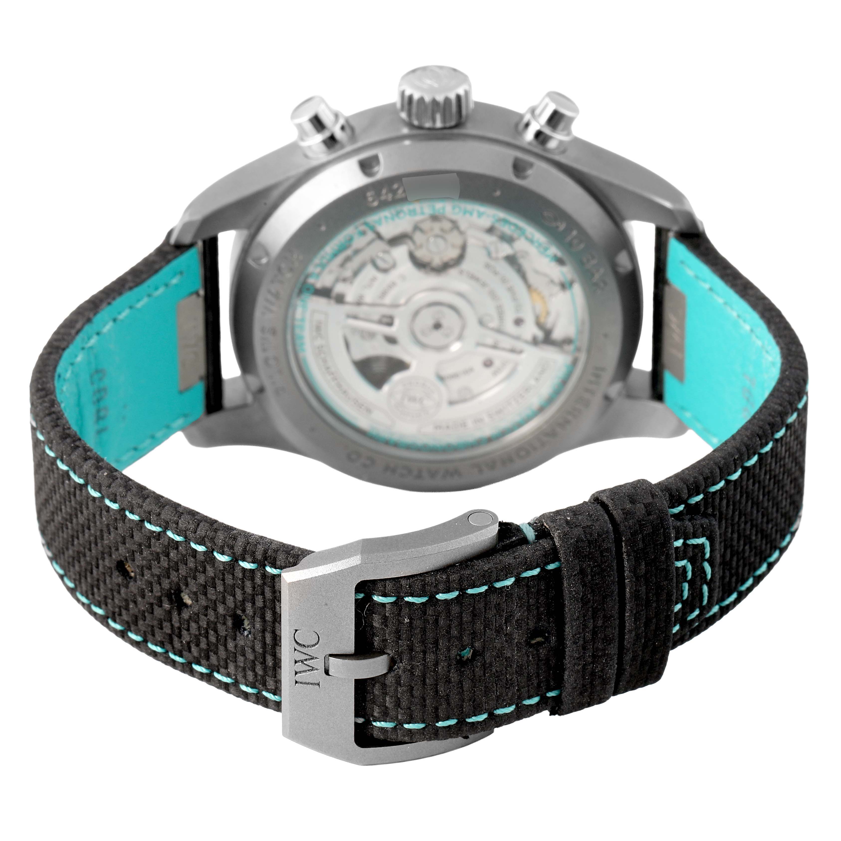 The image shows the back of the IWC Pilot IW370607 Men's Titanium Black Dial watch, featuring its movement and a black strap with blue stitching.