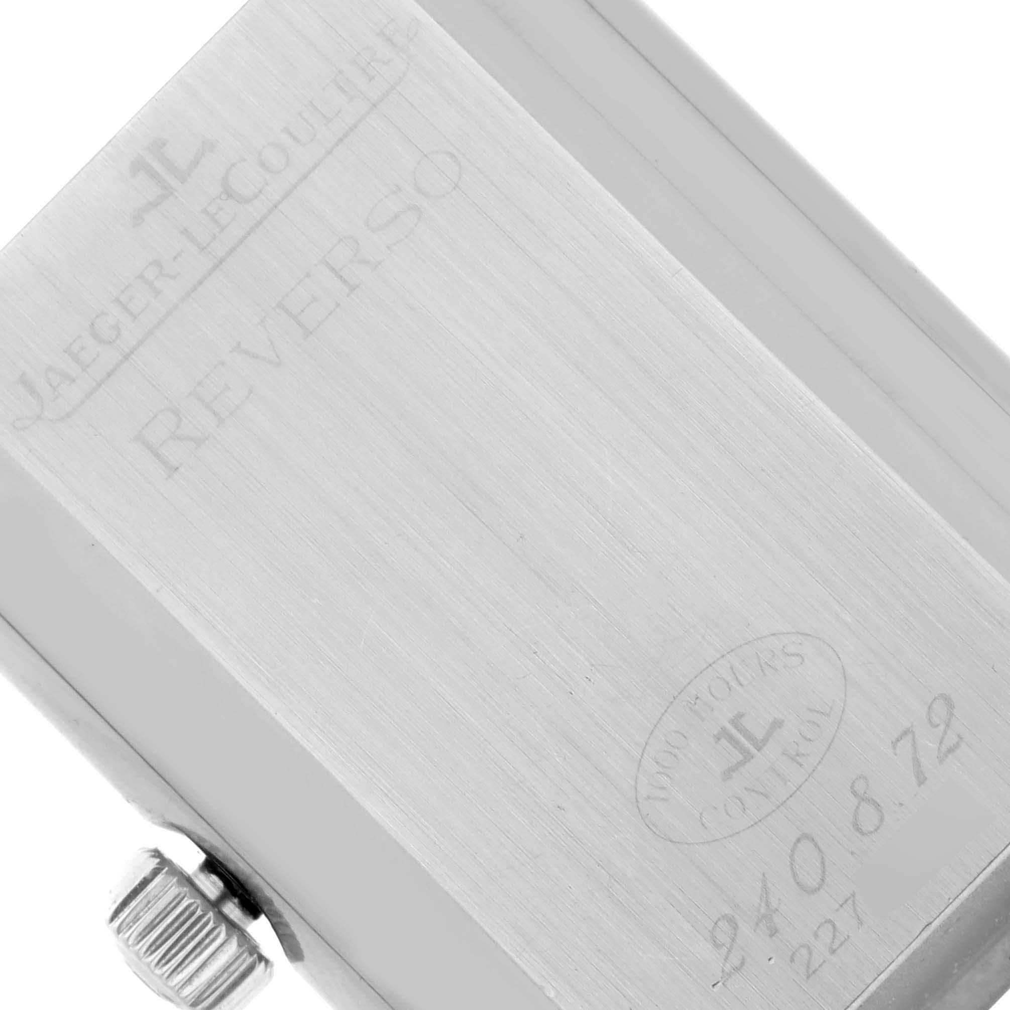 The image shows the back casing of a Jaeger-LeCoultre Reverso watch, featuring engravings and the crown on the side.