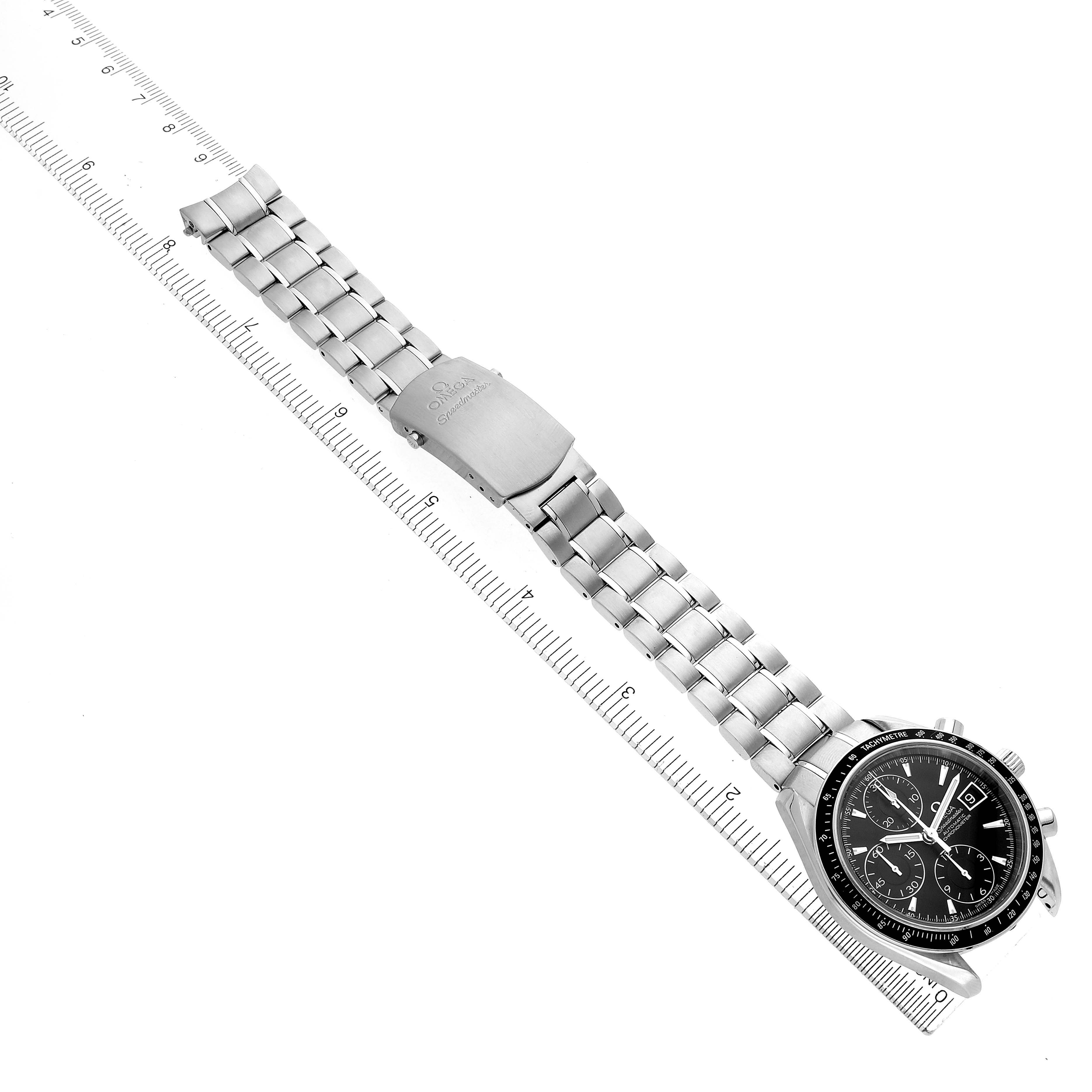 The Omega Speedmaster 3210.50.00 Men
s Stainless Steel Black Dial 3210.50.00 Men
s Stainless Steel Black Dial watch is shown from a top view, displaying the full bracelet, clasp, and watch face alongside a ruler.