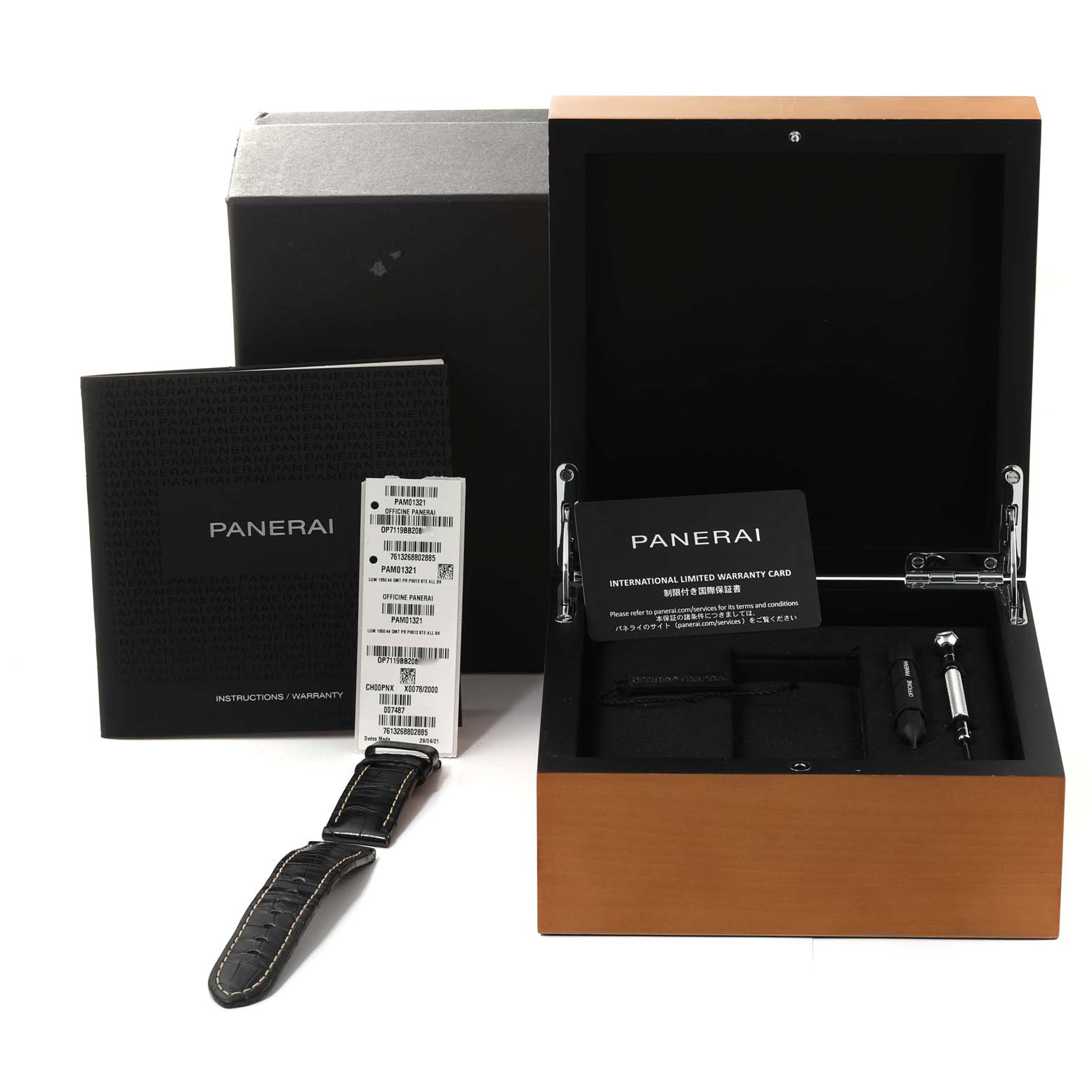 The image shows a Panerai Luminor PAM01321 Men
s Stainless Steel Black Dial PAM01321 Men
s Stainless Steel Black Dial watch box with the open lid, displaying an international warranty card, tools, and an extra strap.