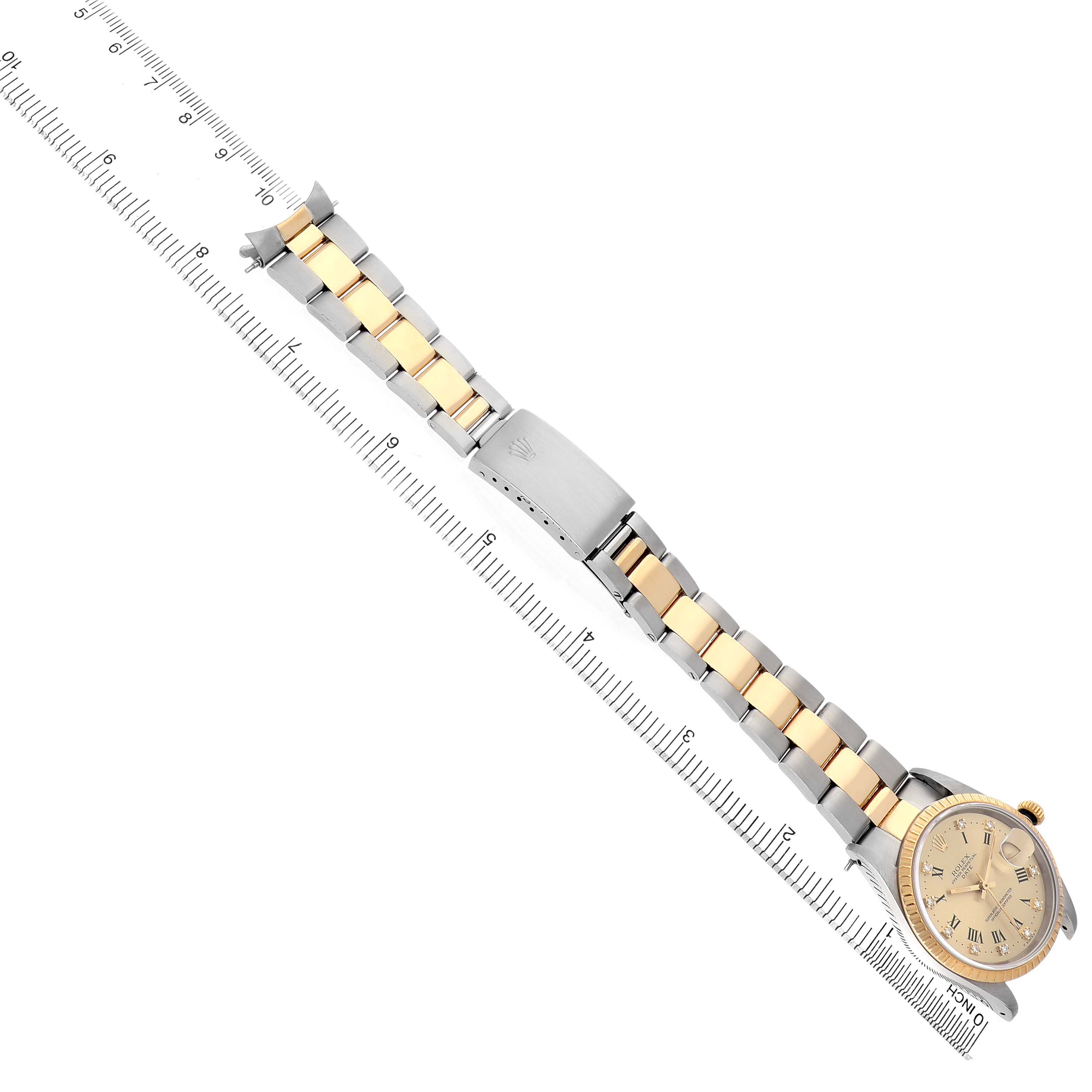 The image shows a Rolex Date 15223 Men's Steel and Gold (two tone) Champagne Dial watch displayed flat, highlighting its band and clasp, next to a ruler for scale.