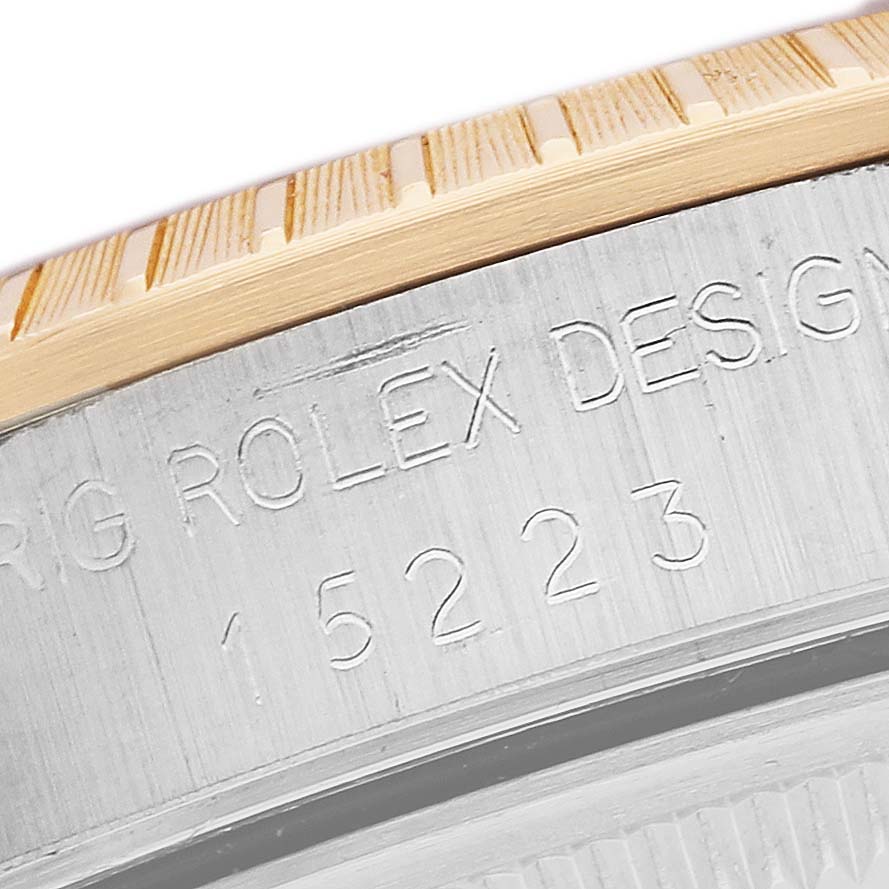 The image shows a close-up of the engraved side of a Rolex Date 15223 Men's Steel and Gold (two tone) Champagne Dial model, featuring the bezel and case details.