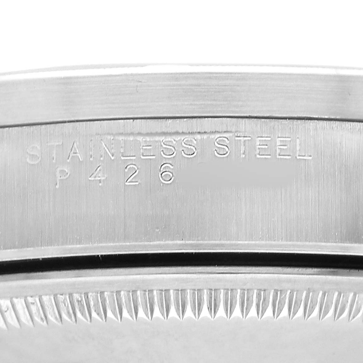 The image shows a close-up of the engraved side of a Rolex Date 15210 Men's Stainless Steel White Dial model, highlighting the stainless steel marking.