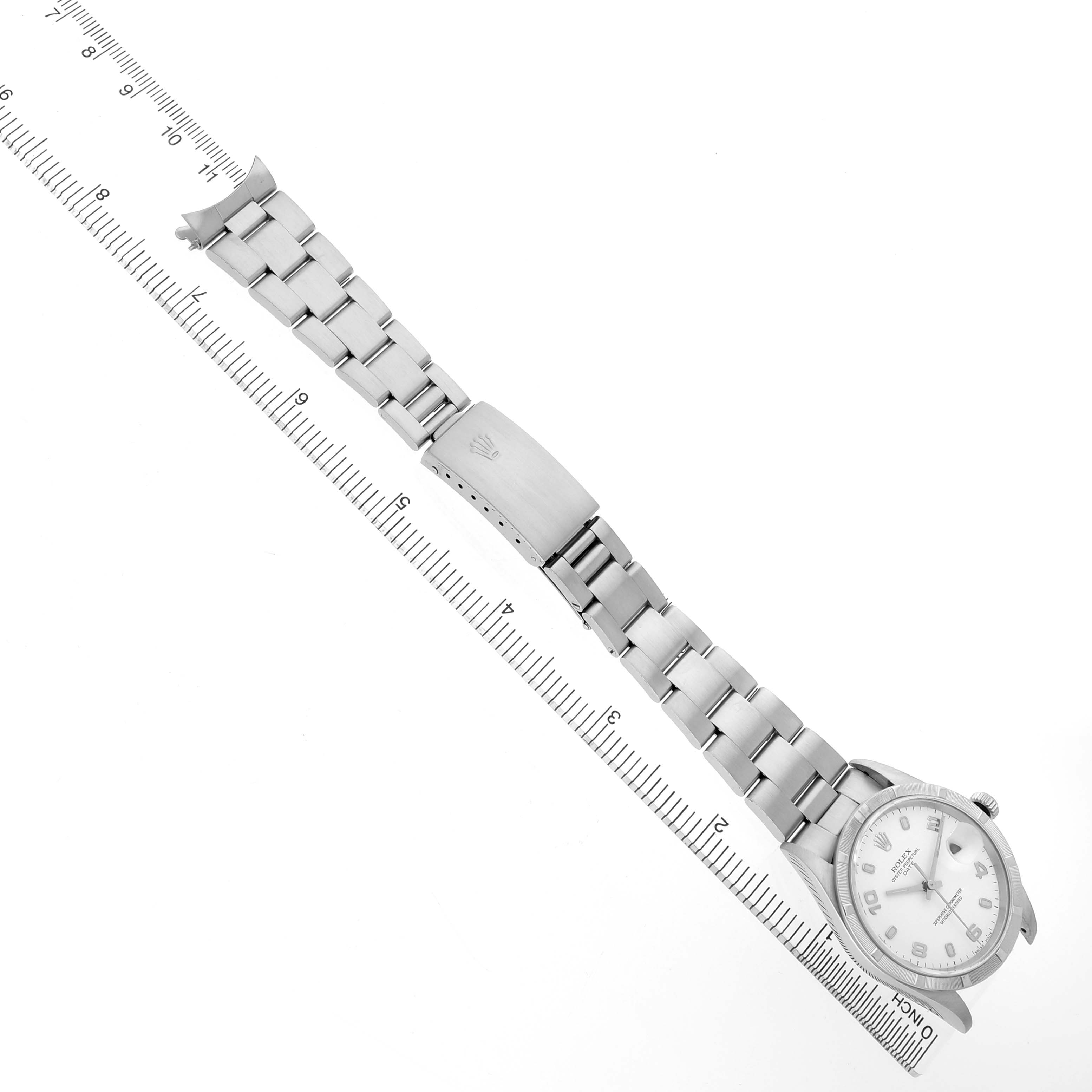 The image shows a Rolex Date 15210 Men's Stainless Steel White Dial watch from a top view, featuring the watch face, bracelet, and clasp, aligned with a measuring ruler.