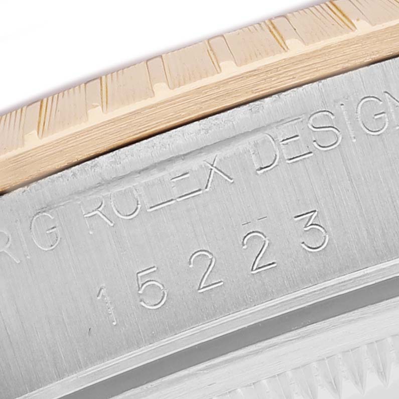 The image shows a close-up of the bezel and engraved model number on a Rolex Date 15223 Men's Steel and Gold (two tone) Champagne Dial watch.
