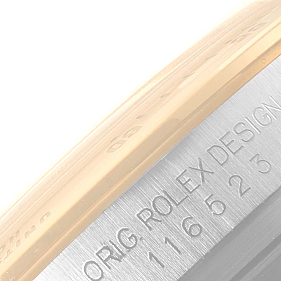 This image shows a close-up of the side bezel and case of a Rolex Daytona 116523 Men's Steel and Gold (two tone) Blue Dial 116523 Men's Steel and Gold (two tone) Blue Dial watch, highlighting the model number and "Rolex Design" engraving.