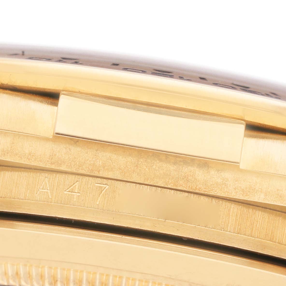 This image shows a close-up of the side view of a Rolex Daytona 16518 Men's Yellow Gold White Dial watch, focusing on the case and engraved markings.