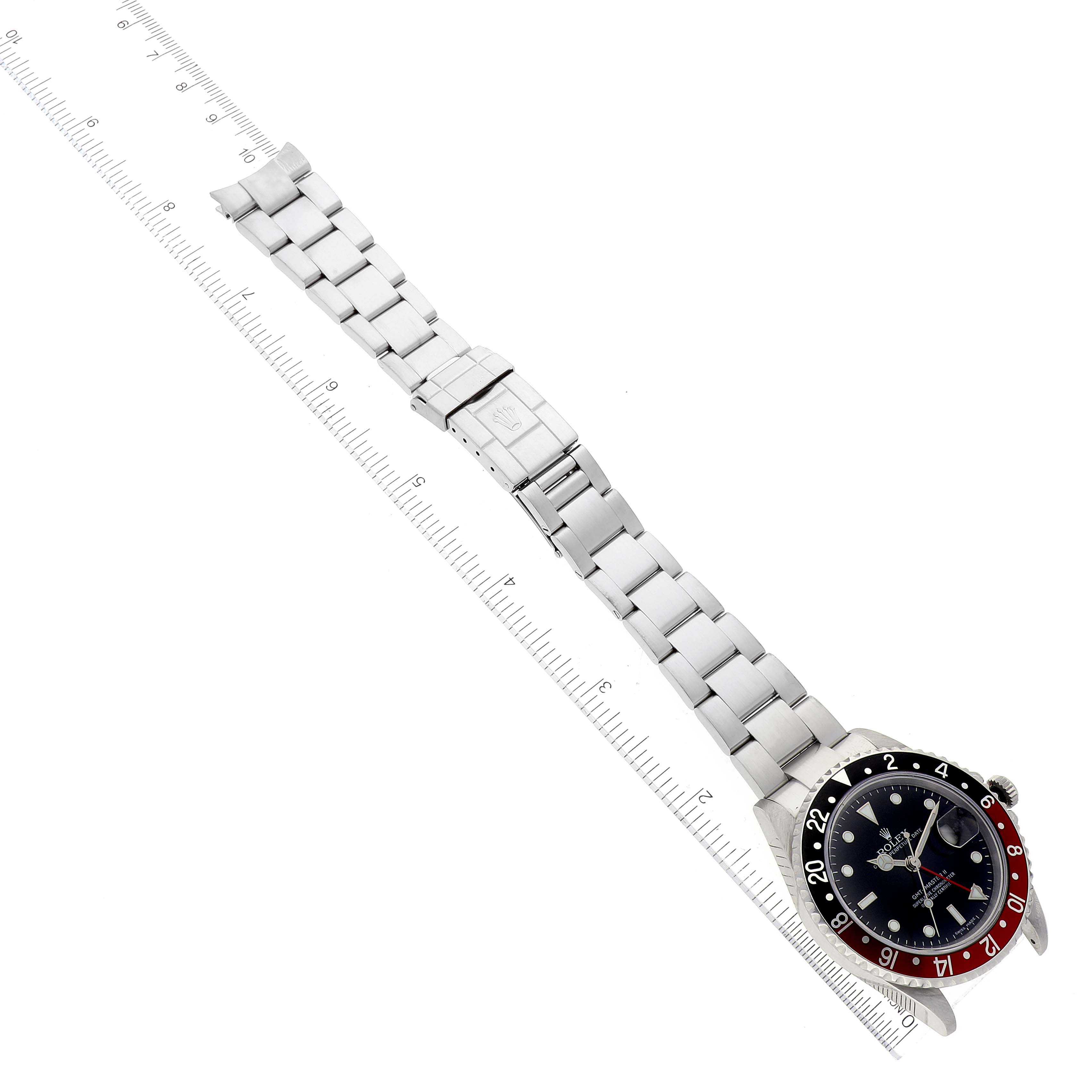 A Rolex GMT-Master 16710 Men's Stainless Steel Black Dial 16710 Men's Stainless Steel Black Dial watch is shown laid flat with its bezel, dial, bracelet, and clasp visible alongside a measuring ruler.