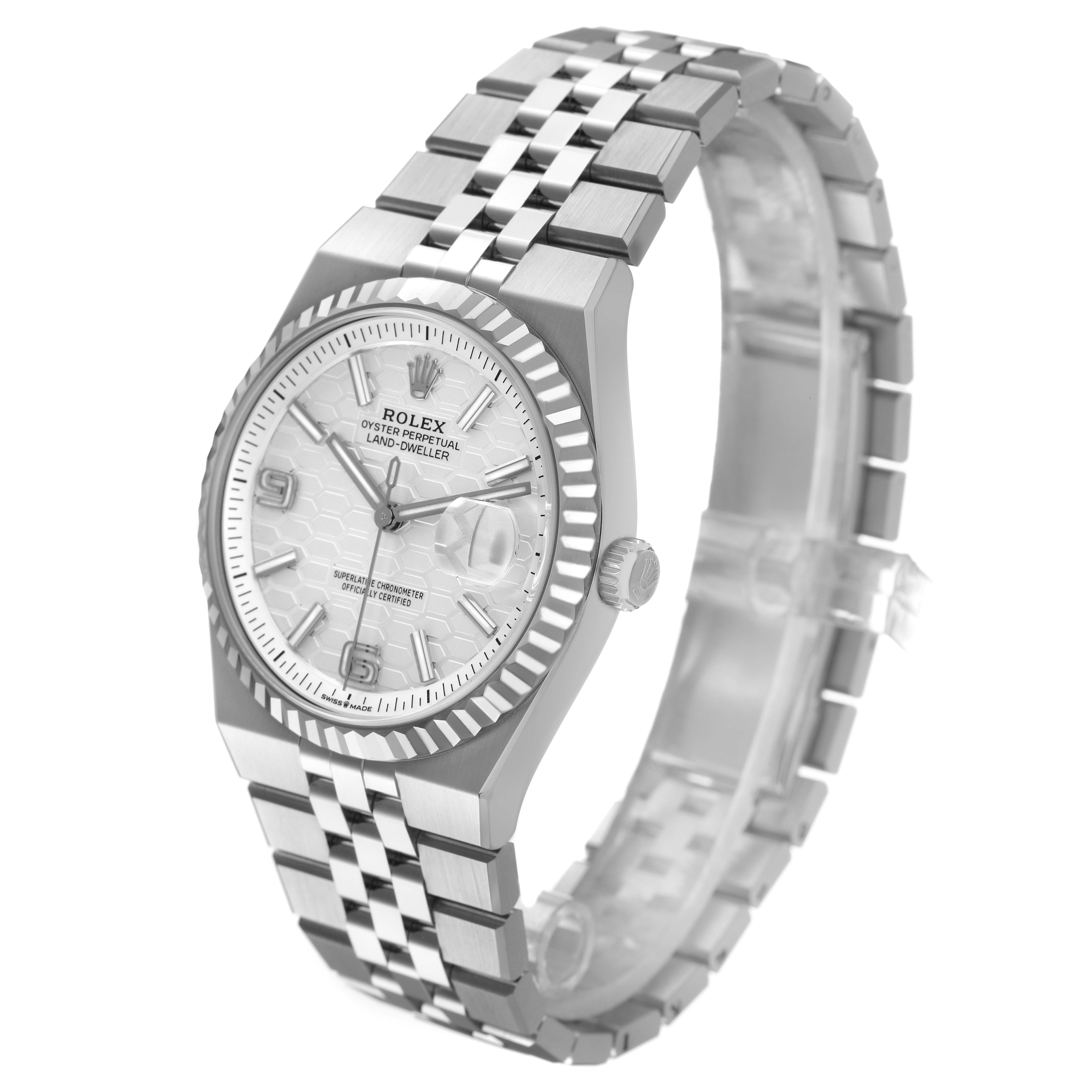 The Rolex Land-Dweller watch is shown at a three-quarter angle, highlighting the bezel, dial, crown, and bracelet.