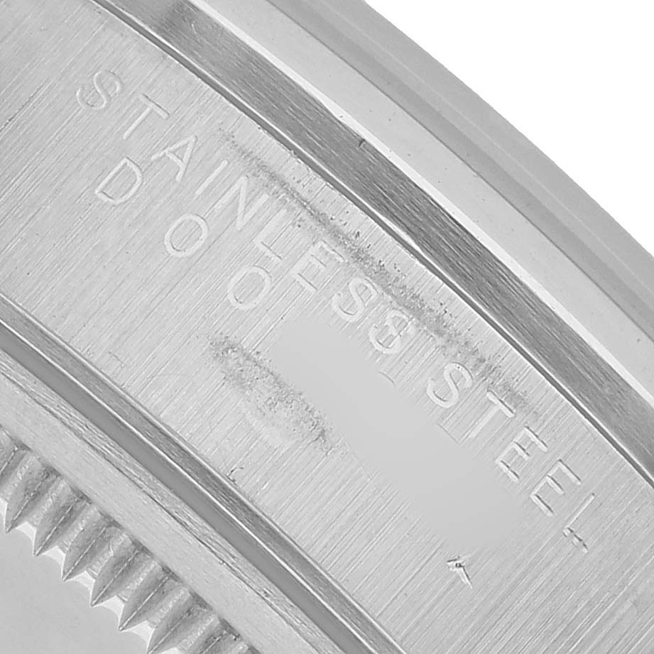 The image shows a close-up of the bezel edge and side of a Rolex Date 15200 Men's Stainless Steel Black Dial, highlighting the "Stainless Steel" engraving.