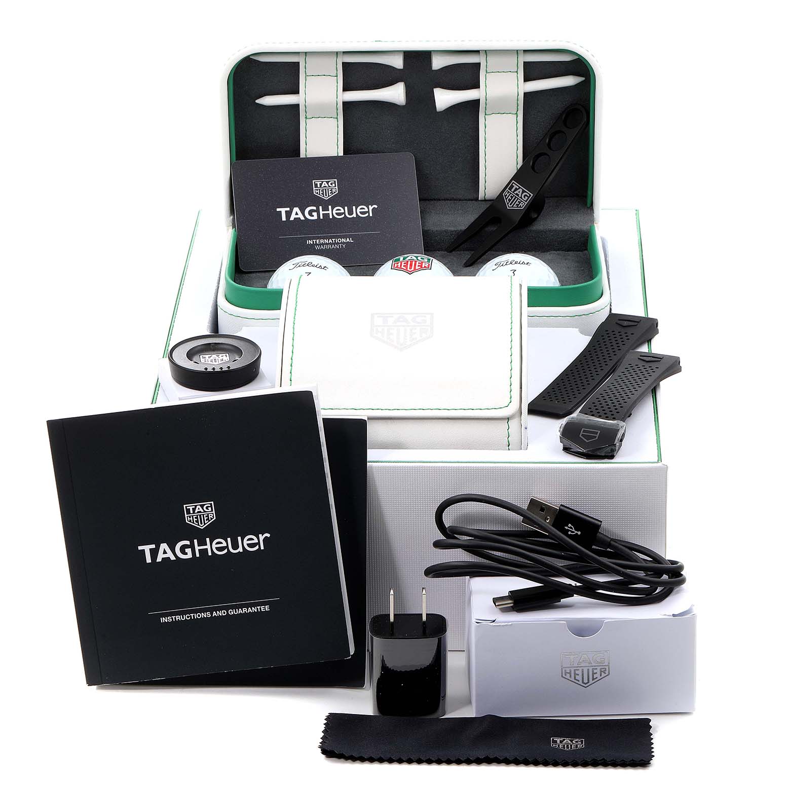 This image shows a top-down view of the Tag Heuer Connected SBG8A82.EB0206 Men's Titanium  SBG8A82.EB0206 Men's Titanium  model watch accessories including straps, a charger, and an international warranty card.