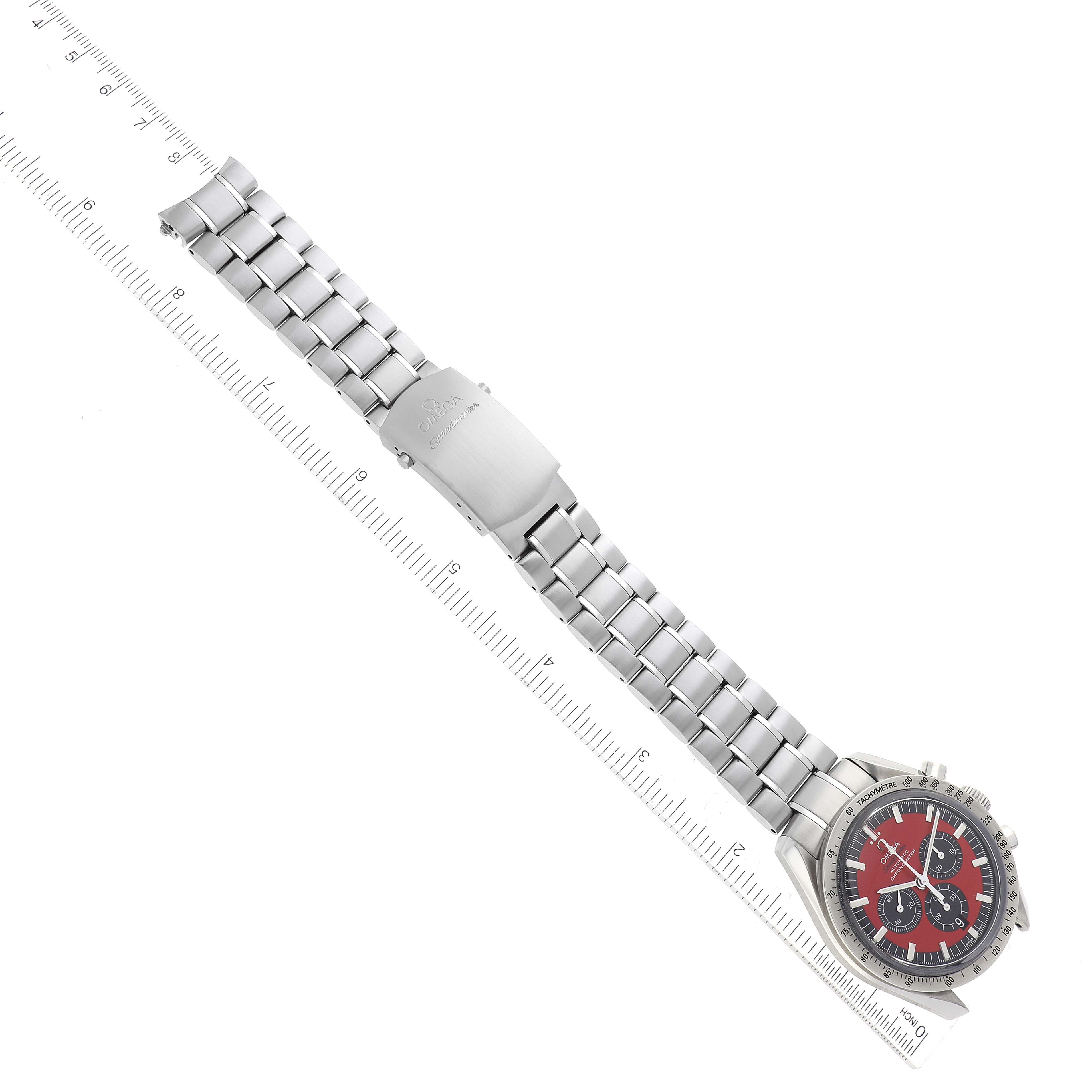 The image shows an Omega Speedmaster 3506.61.00 Men's Stainless Steel Red Dial 3506.61.00 Men's Stainless Steel Red Dial watch laid flat with a metal bracelet fully extended and a ruler for measurement.